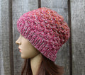Knitted pink beanie on a mannequin head against a wooden background