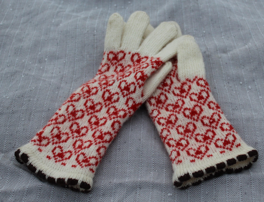 Pair of white gloves with red pattern on a gray fabric background