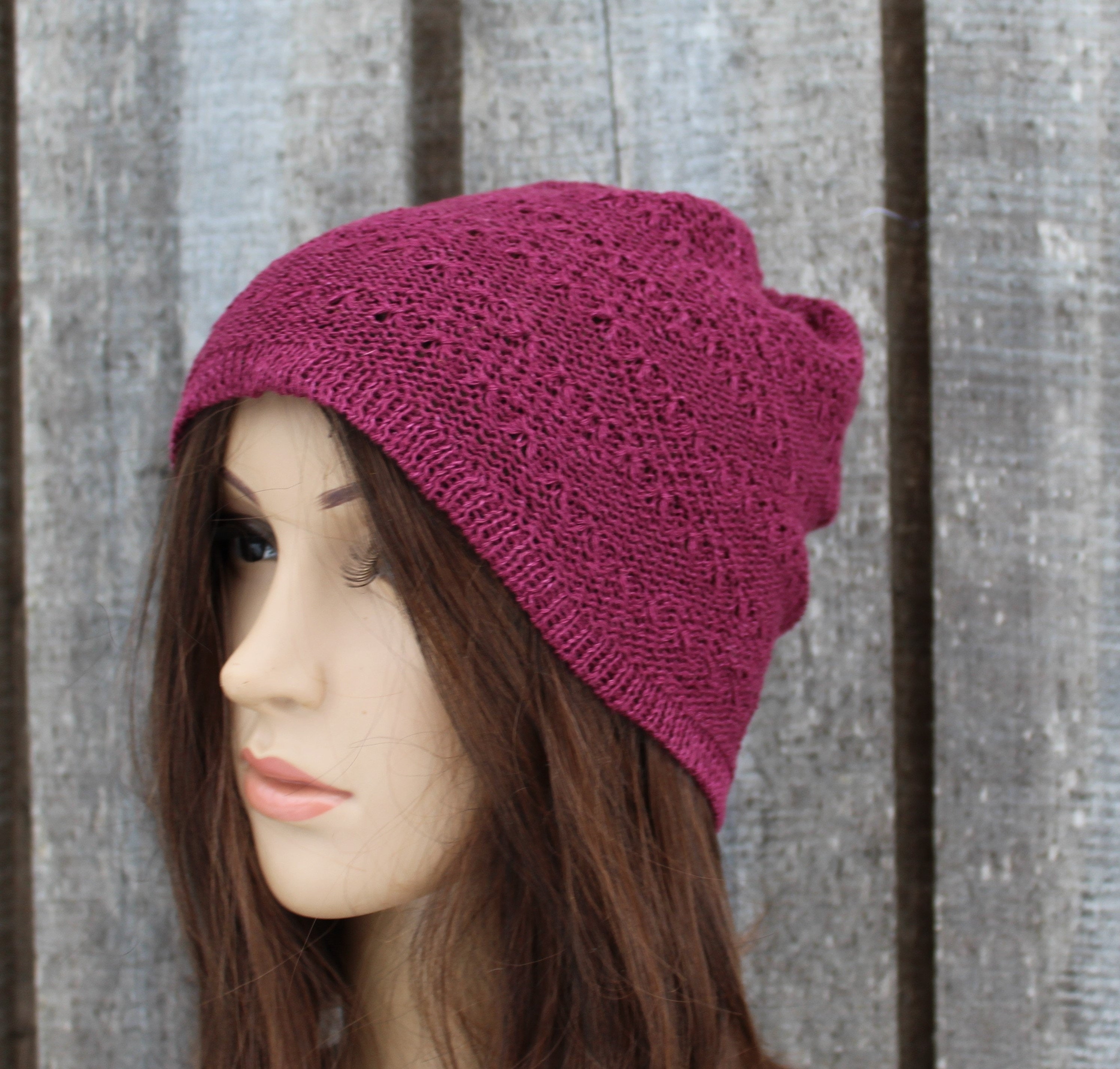 Mannequin head wearing a pink knitted beanie against a wooden background