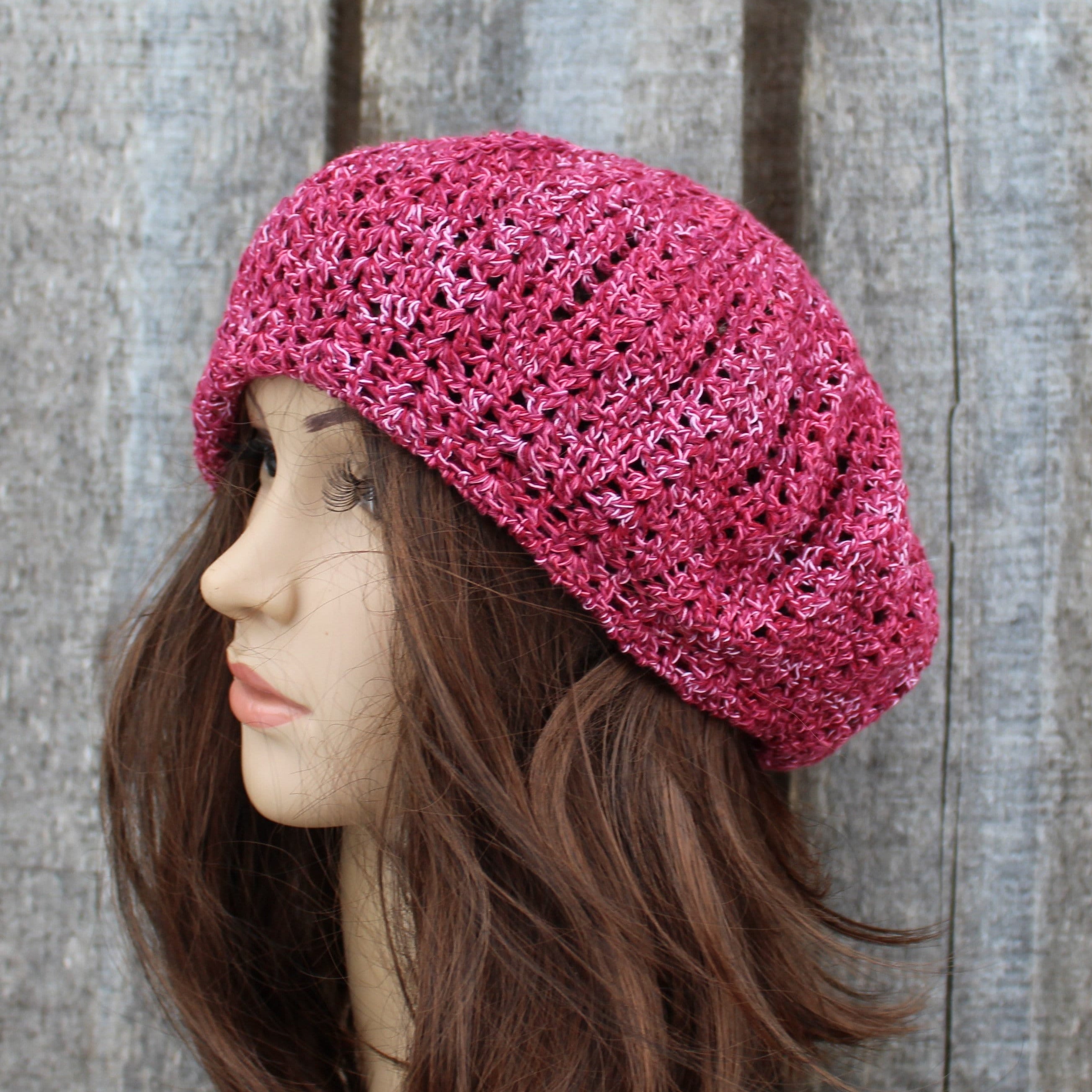 Pink knitted beret worn by a mannequin against a wooden background