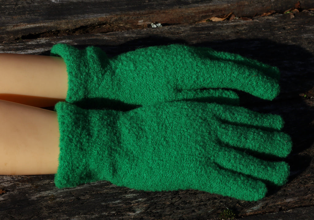 Green gloves worn by a person on a wooden surface