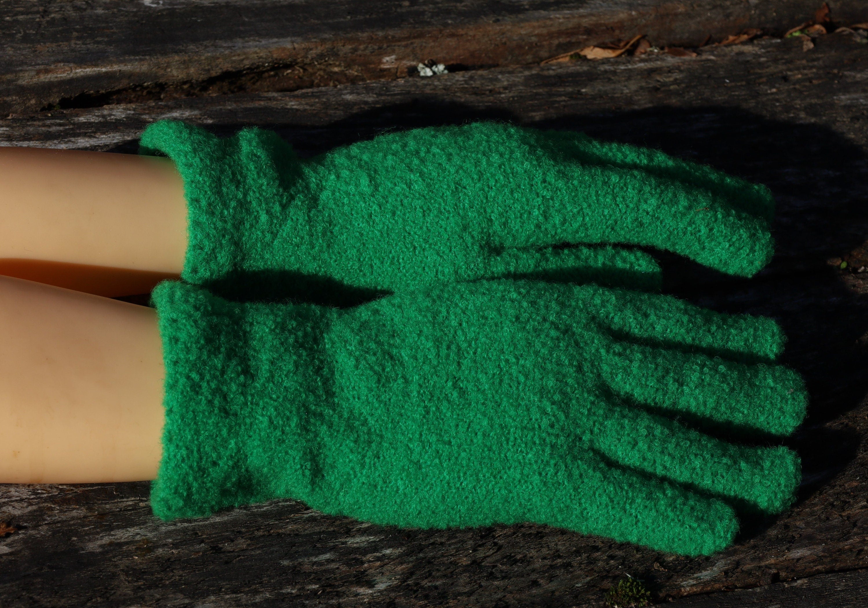 Green gloves worn by a person on a wooden surface