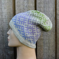 Knitted hat with a geometric pattern on a mannequin head against a wooden background