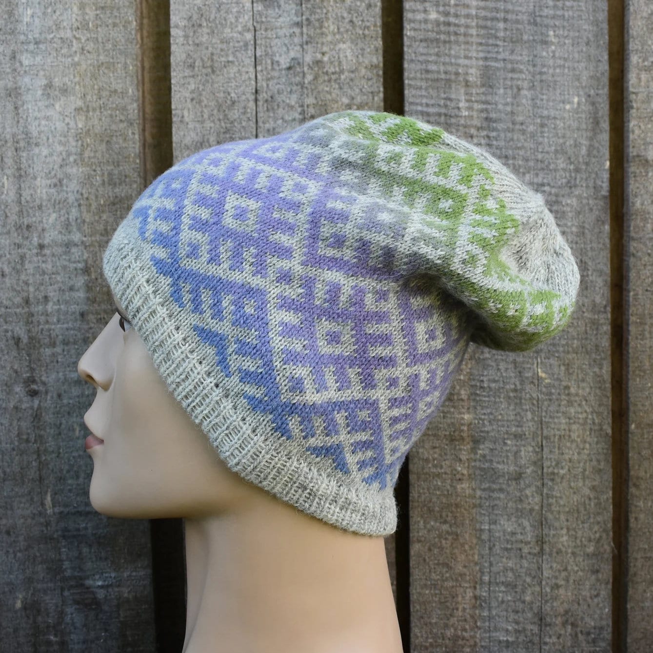 Knitted hat with a geometric pattern on a mannequin head against a wooden background