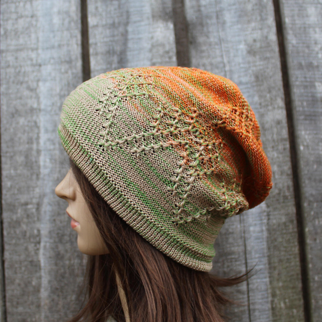 Knitted hat with gradient colors worn by a mannequin against a wooden background