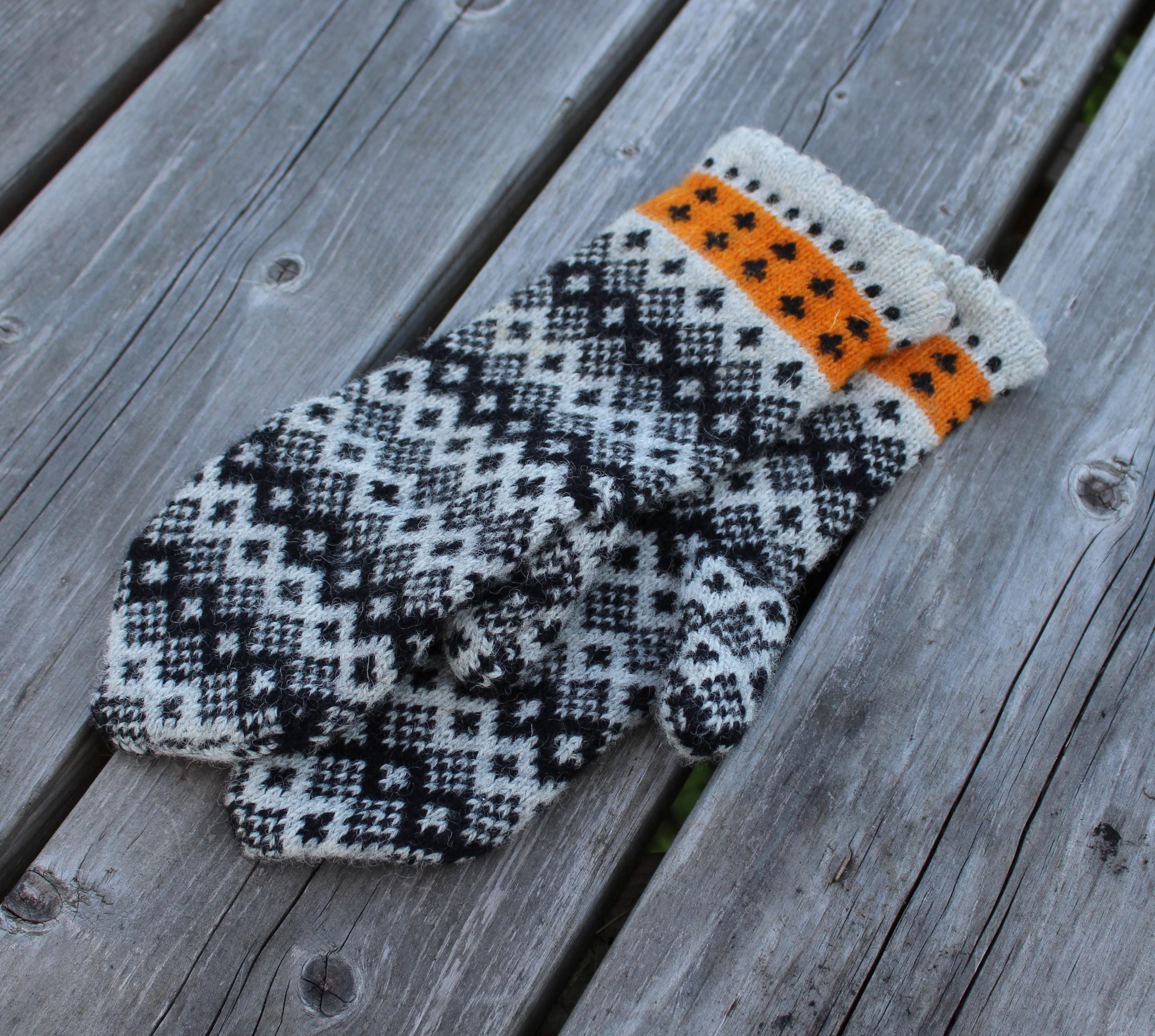 Pair of knitted mittens with a geometric pattern on a wooden surface