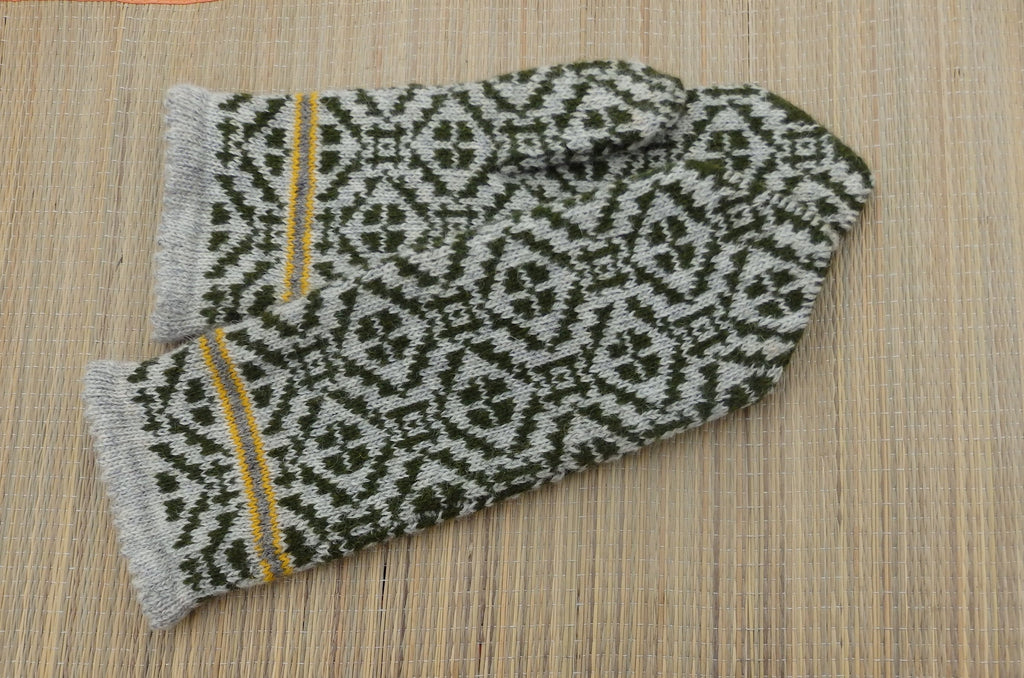 Pair of knitted mittens with a geometric pattern on a wooden surface