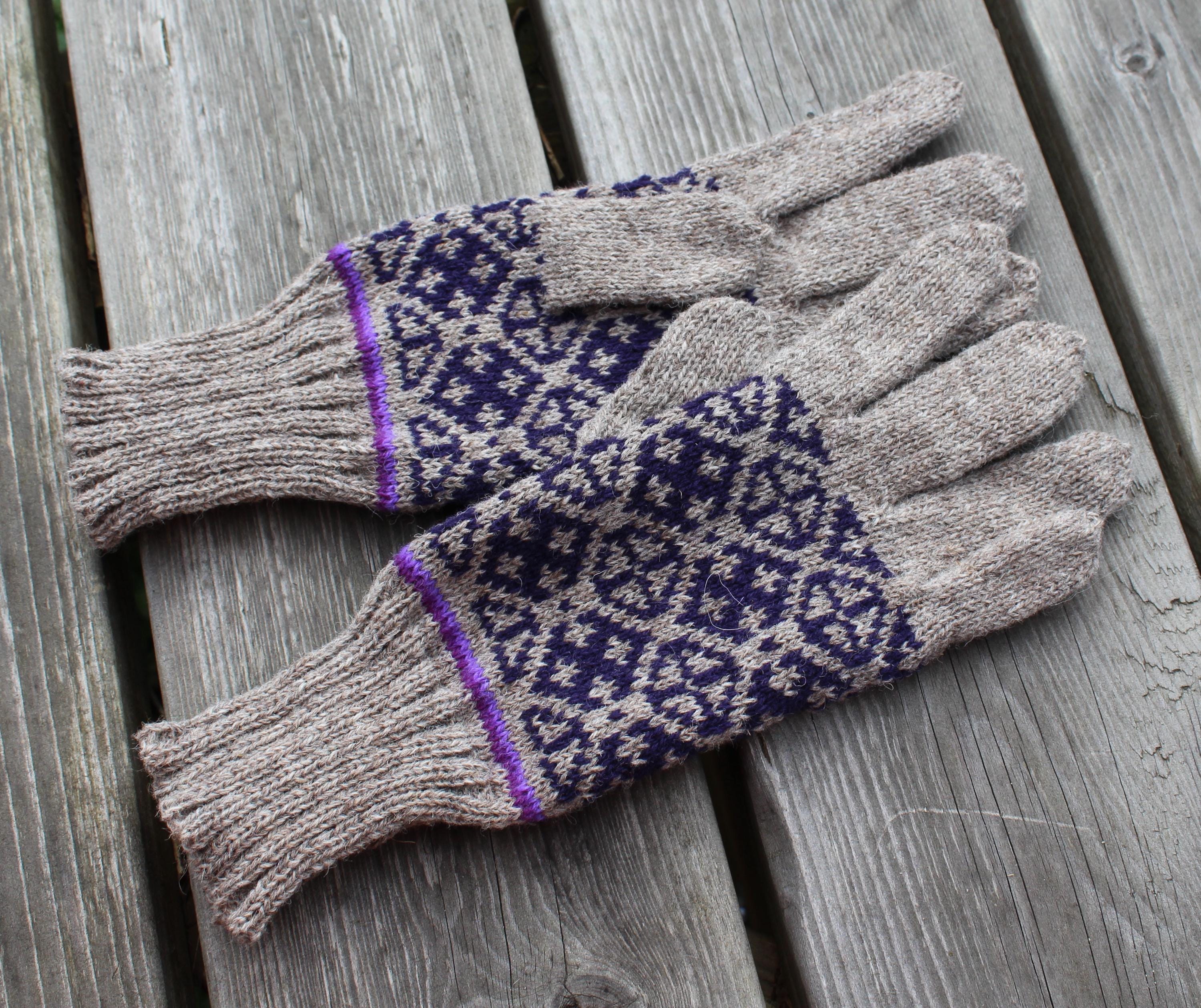 Pair of gray gloves with purple pattern on a wooden surface