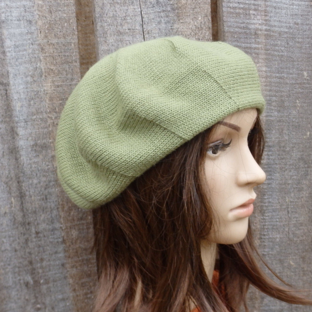 Green knitted beret on a mannequin head against a wooden background