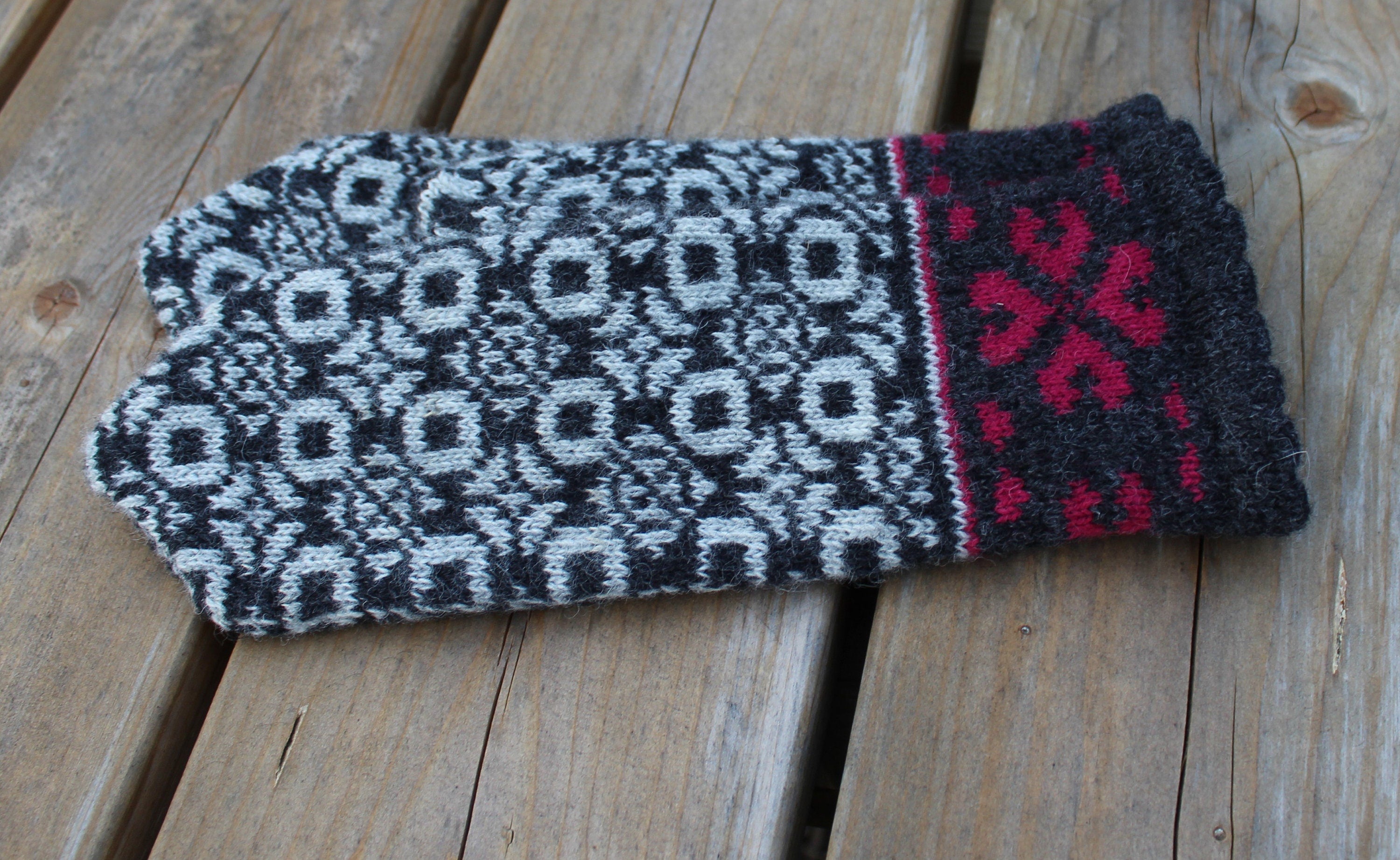 Knitted mitten with geometric pattern on a wooden surface