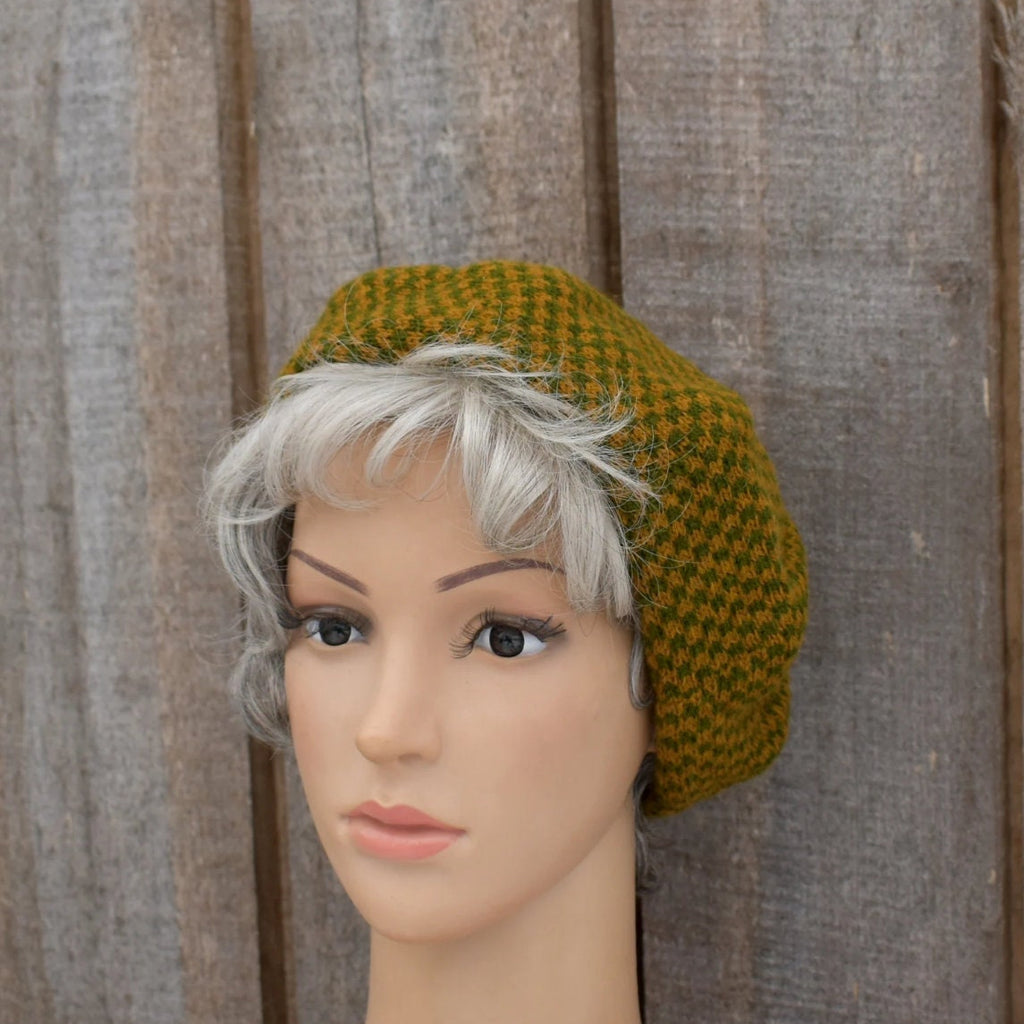 Mannequin head wearing a green knitted hat against a wooden background