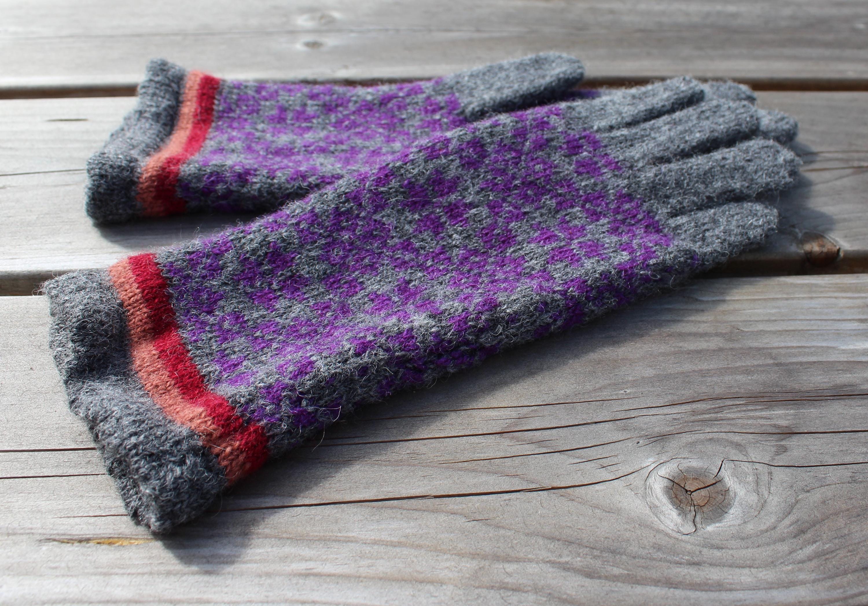 Pair of gray and purple gloves with red accents on a wooden surface