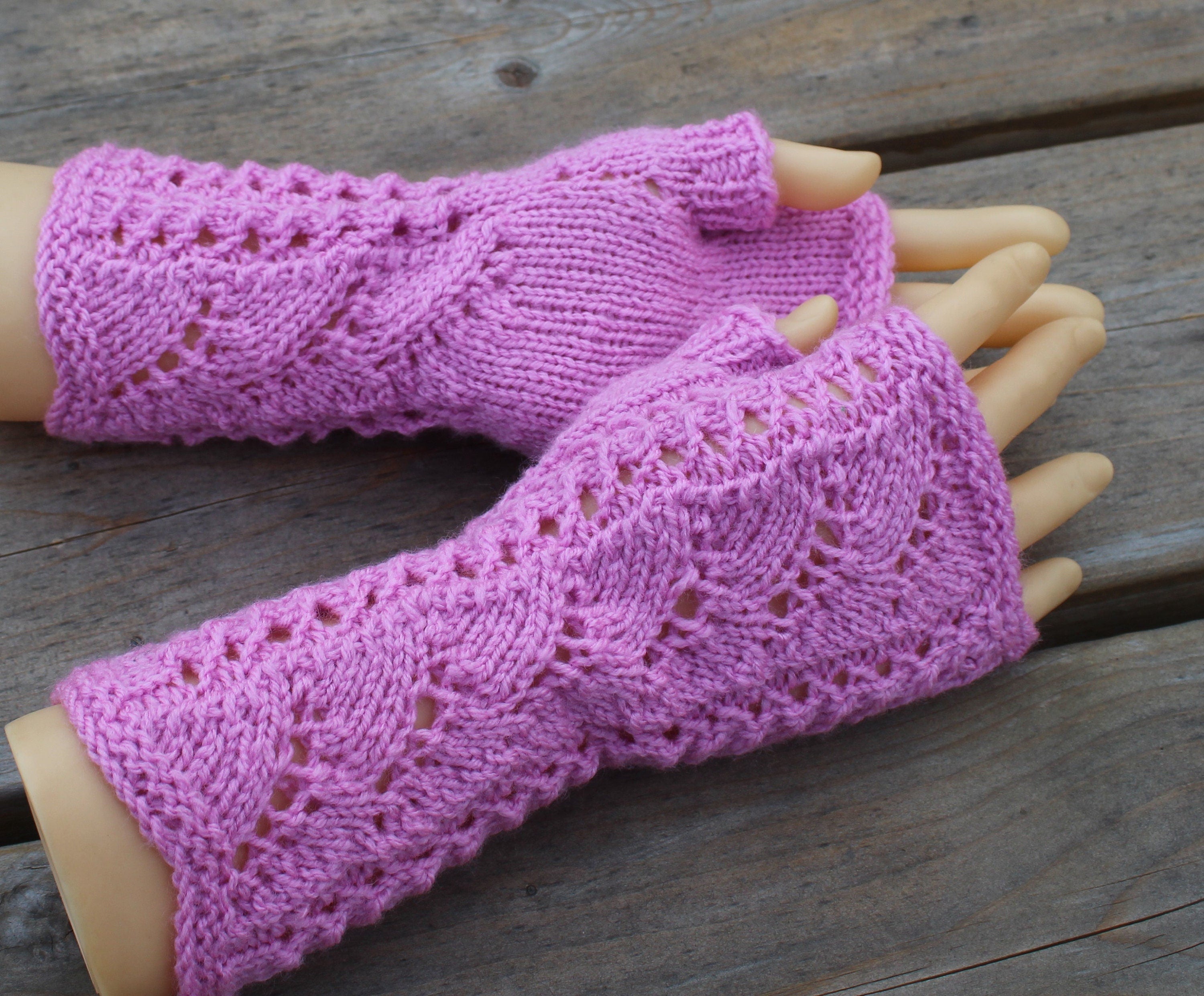 Pink knitted fingerless gloves on a wooden surface