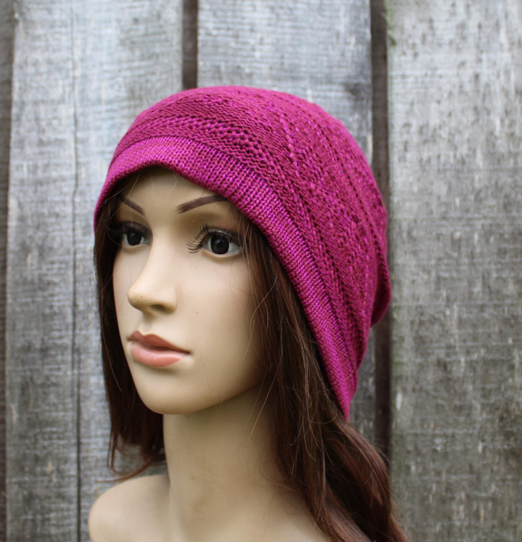 Mannequin head wearing a bright pink knitted hat against a wooden background
