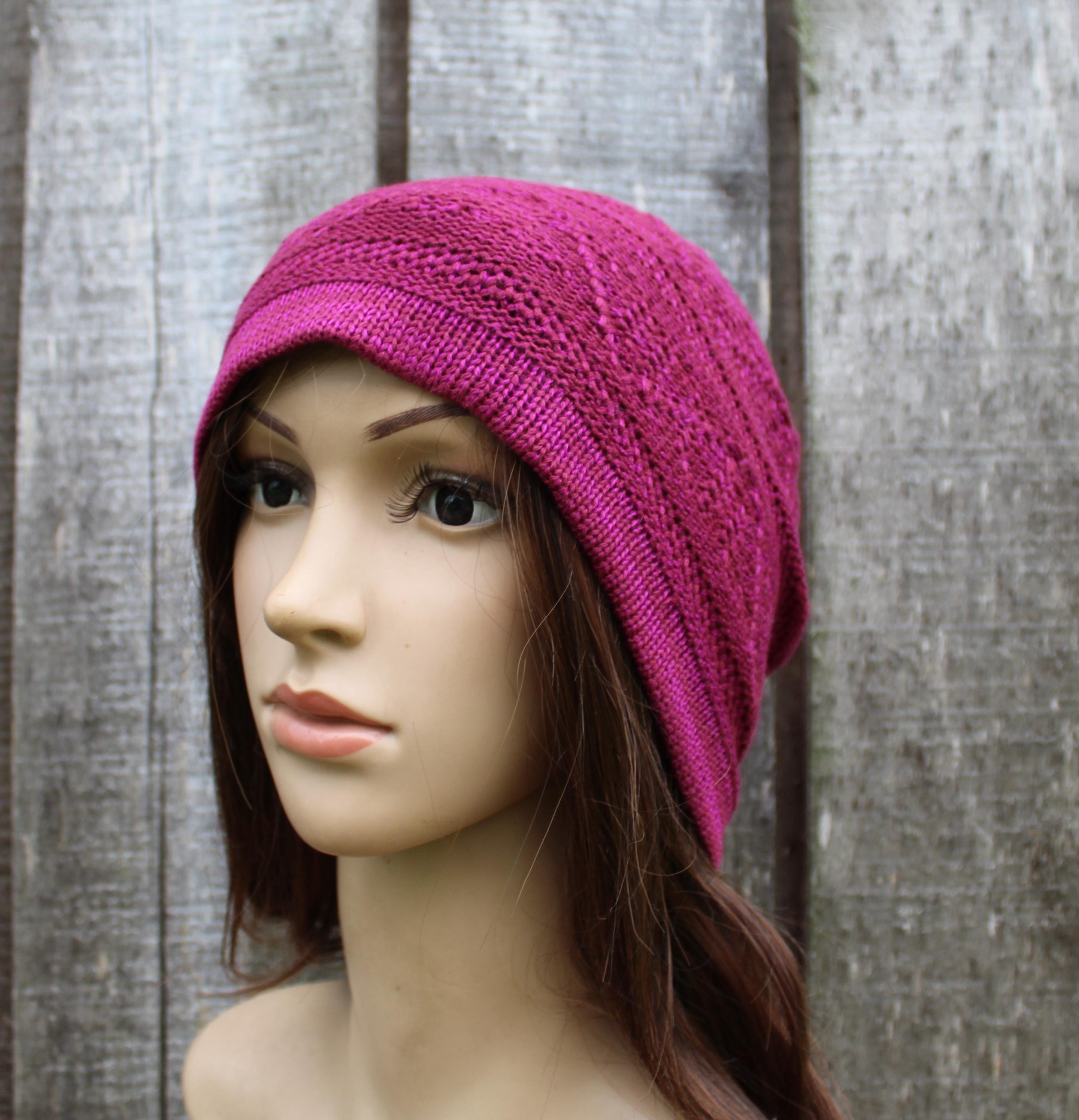 Mannequin head wearing a bright pink knitted hat against a wooden background