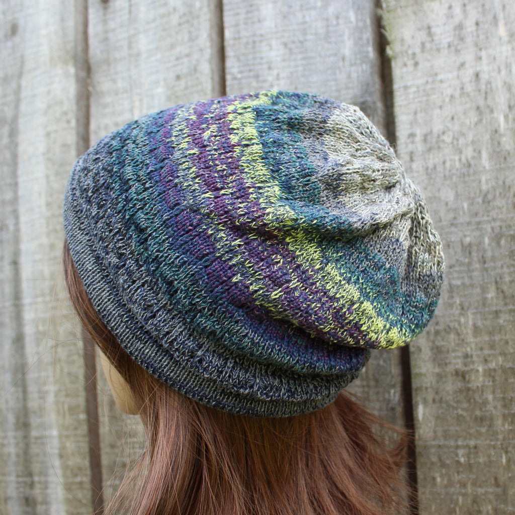 Multicolored knit beanie worn by a person against a wooden background