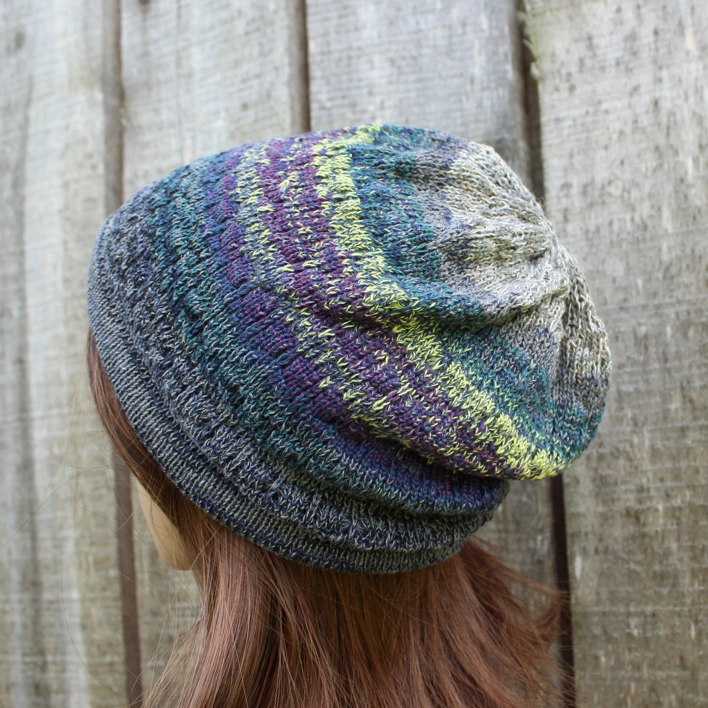 Multicolored knit beanie worn by a person against a wooden background