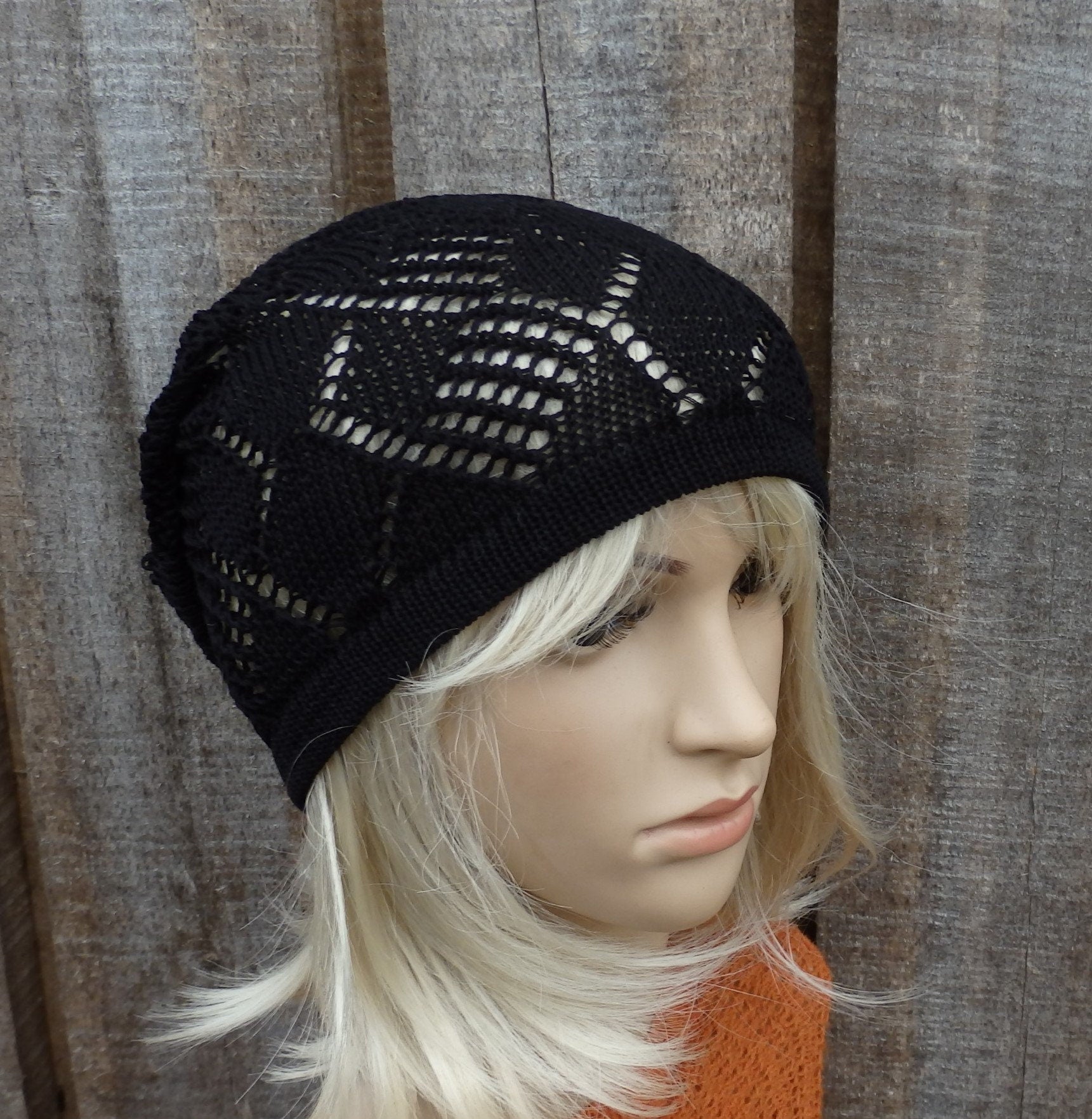 Black knit beanie on a mannequin head against a wooden background