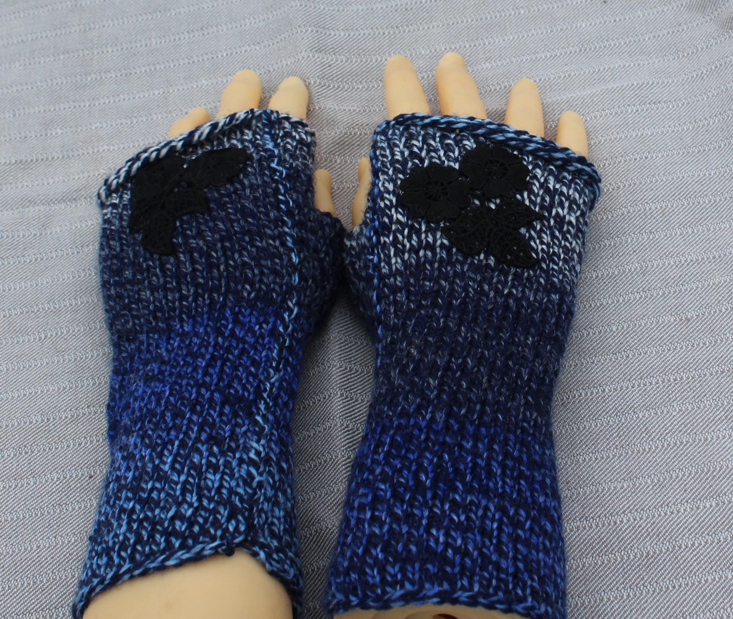 Blue knitted fingerless gloves with black accents on a gray background