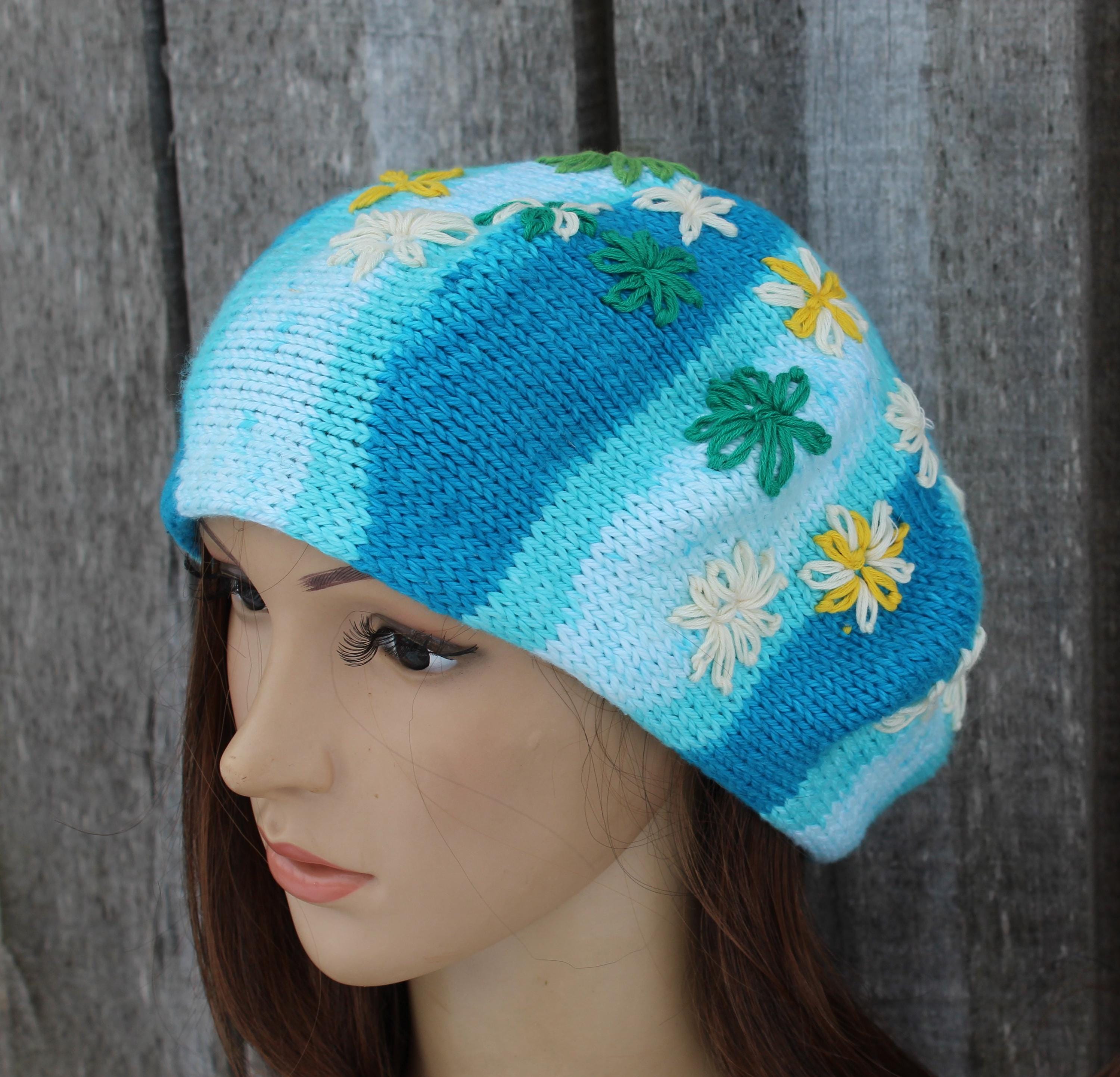 Knitted hat with floral patterns on a mannequin head against a wooden background