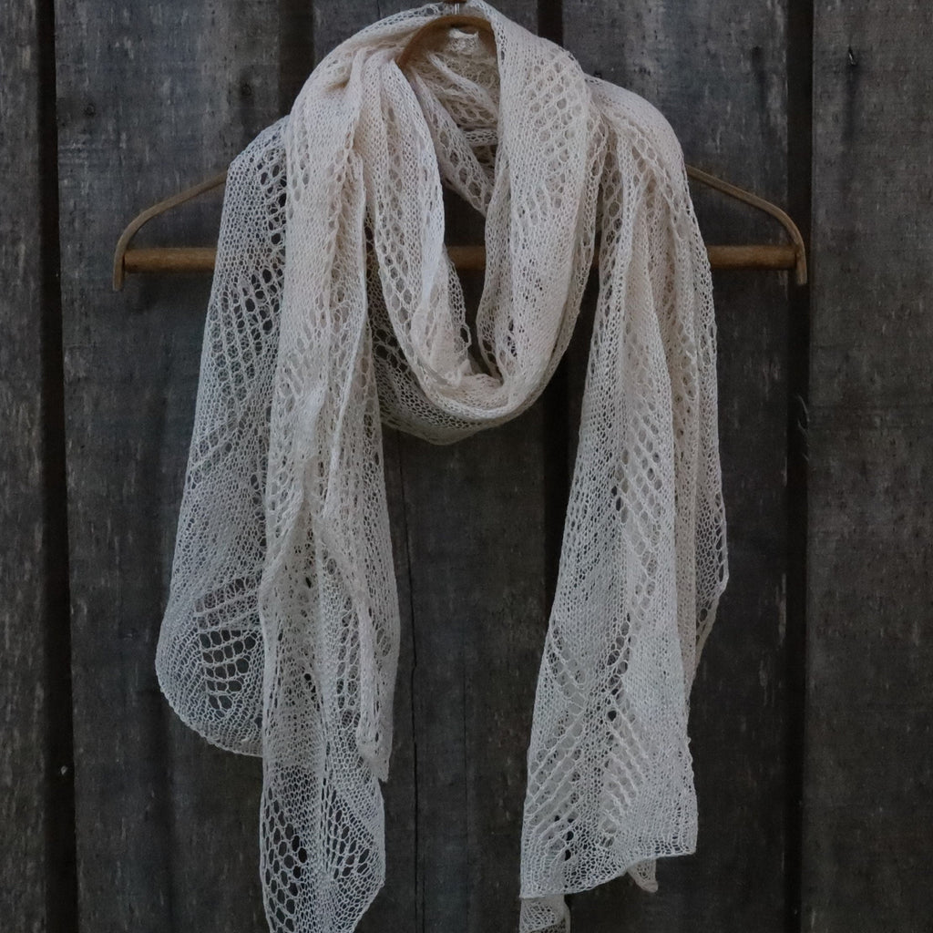 Knitted scarf draped over a wooden hanger against a dark wooden background