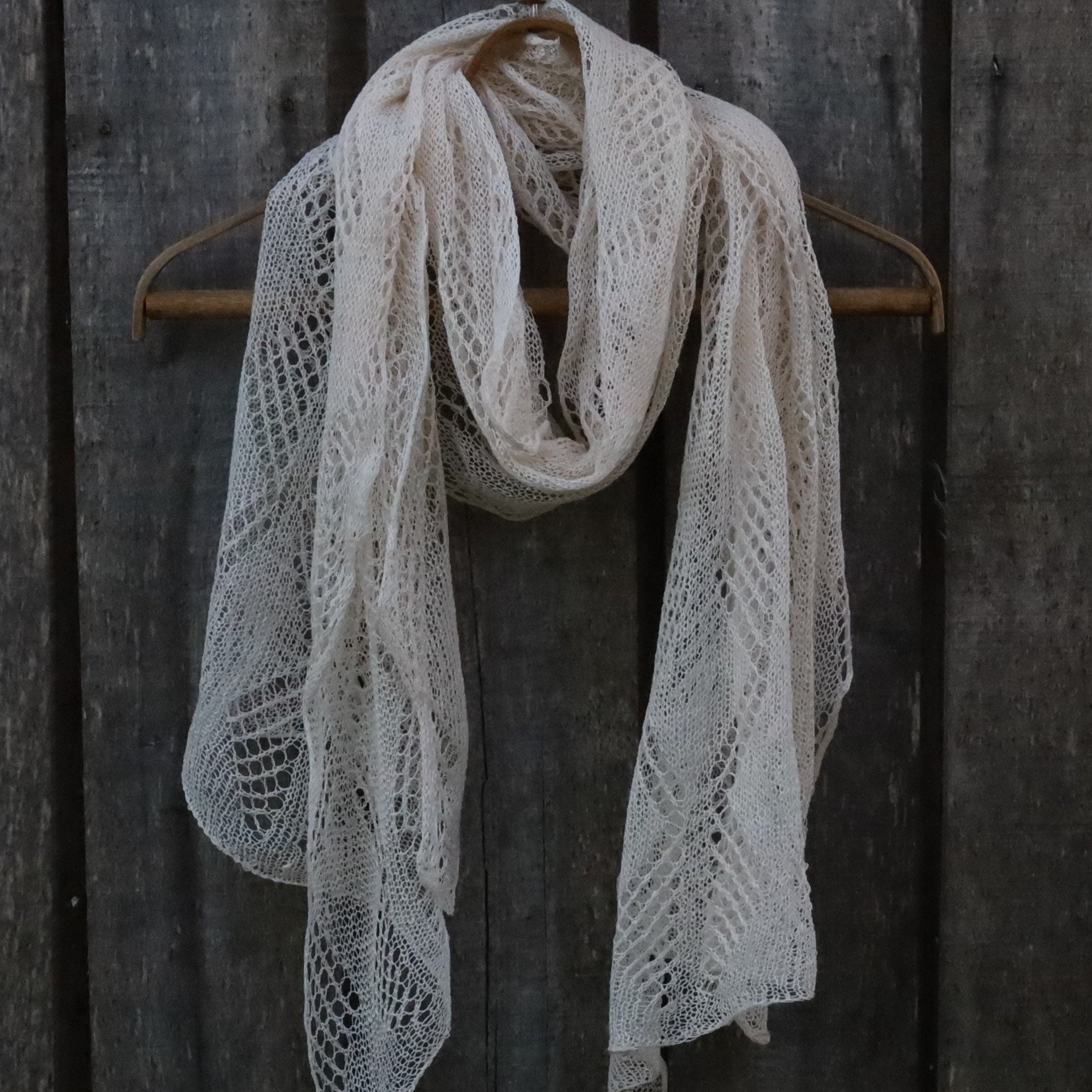 Knitted scarf draped over a wooden hanger against a dark wooden background