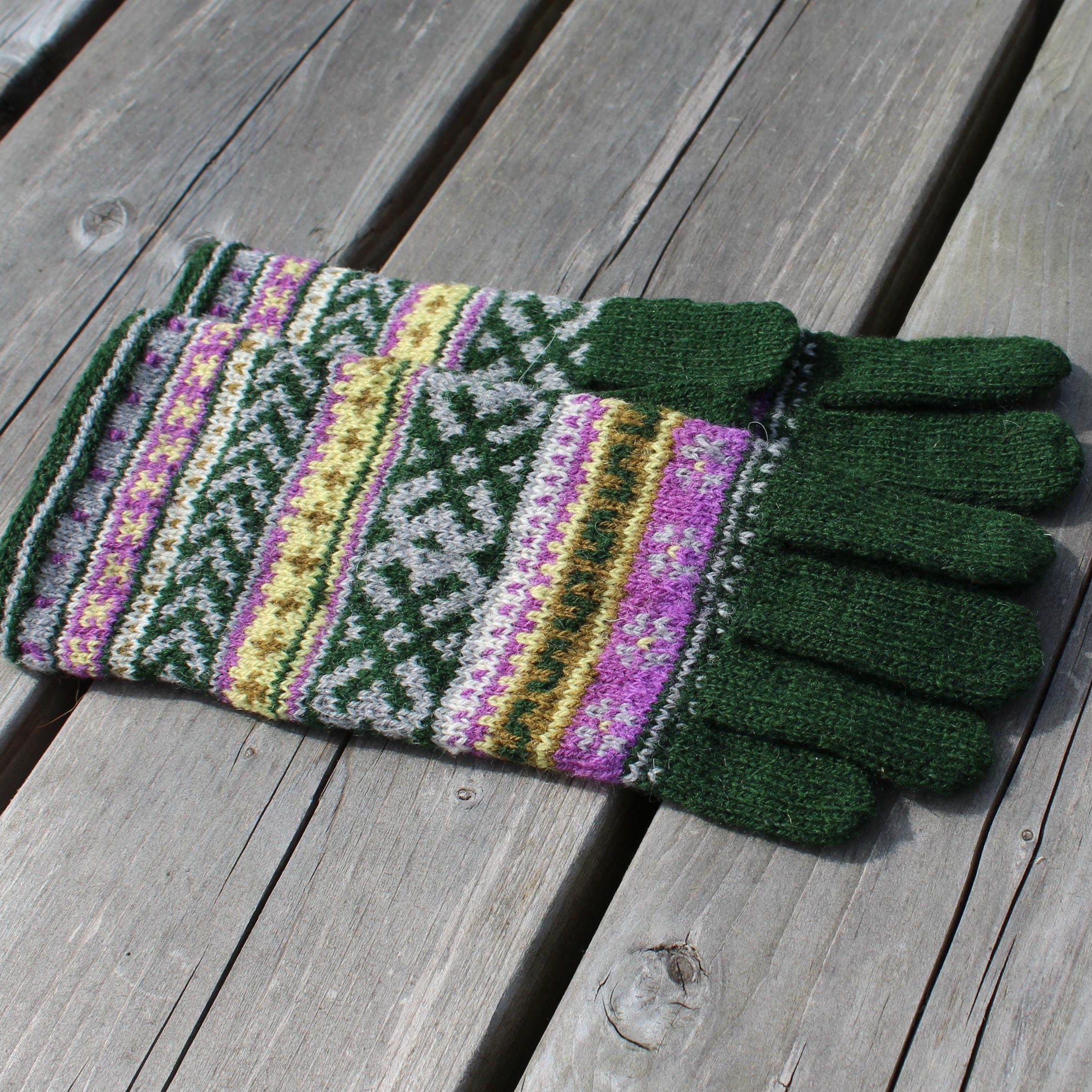 Pair of green and patterned gloves on a wooden surface