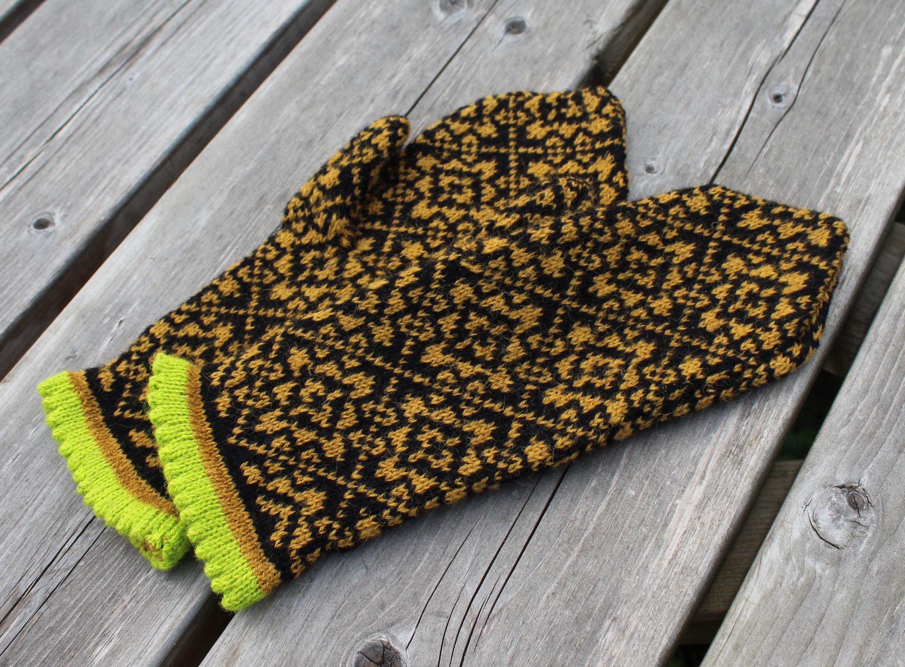 Pair of black and yellow patterned mittens on a wooden surface