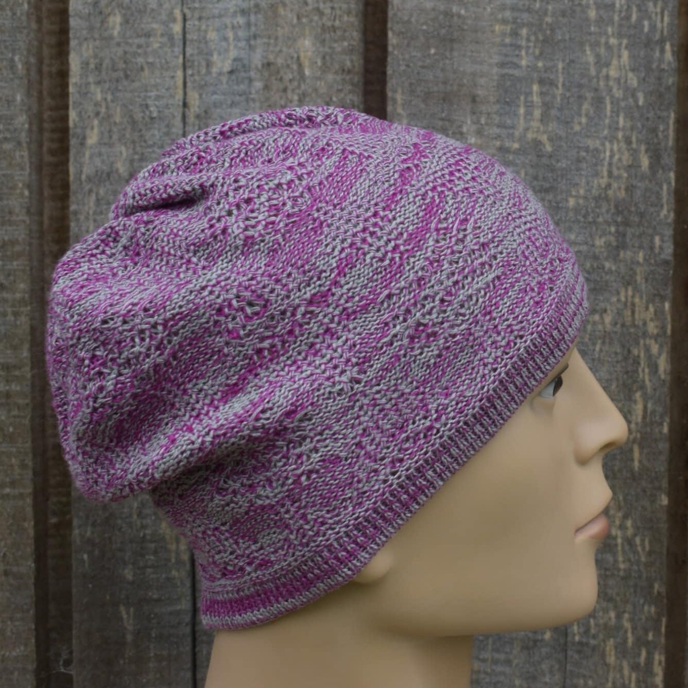 Purple knitted hat on a mannequin head against a wooden background