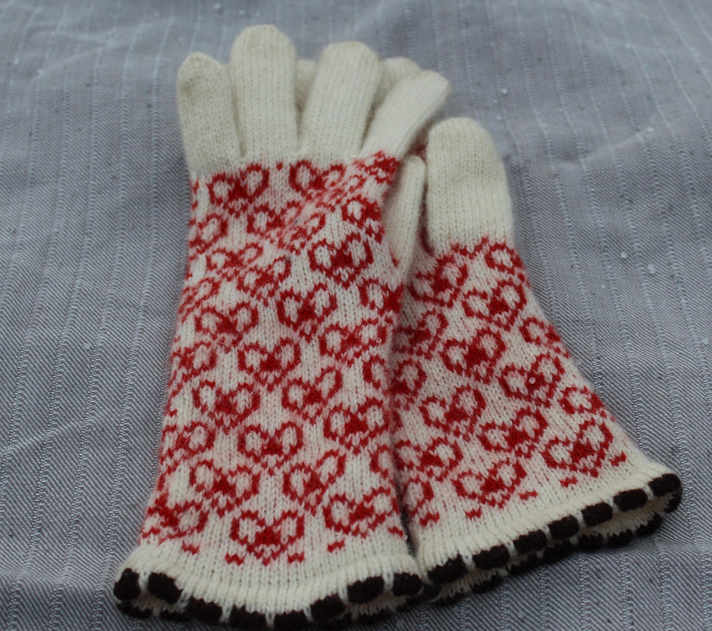 Pair of white gloves with red pattern on a gray fabric background