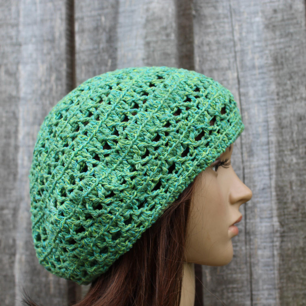 Green crochet hat on a mannequin head against a wooden background