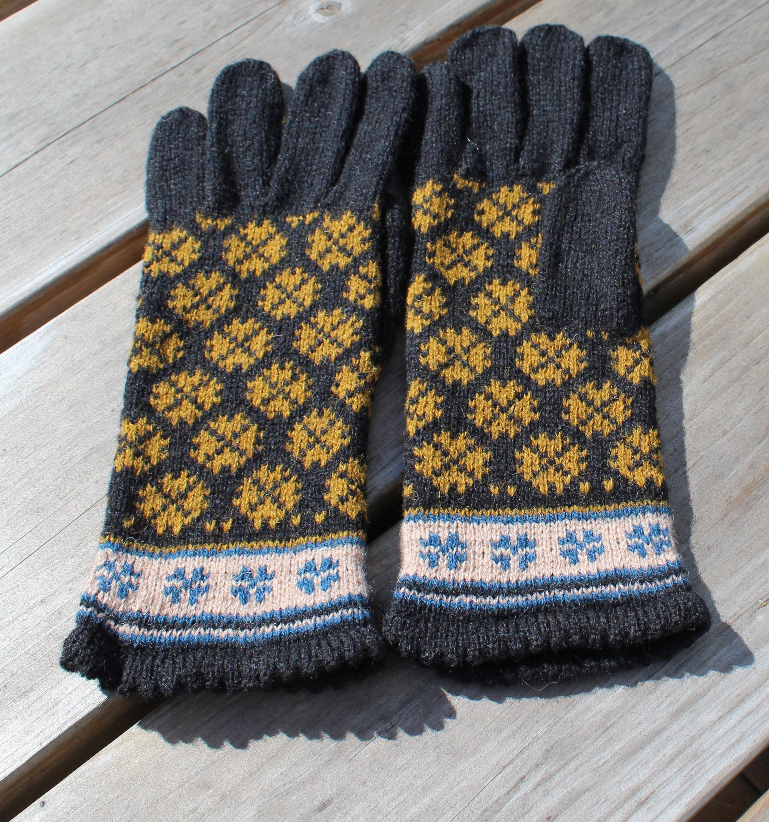 Pair of knitted gloves with a geometric pattern on a wooden surface