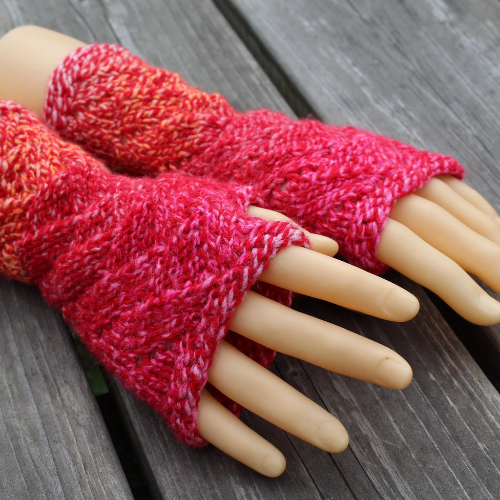 Red knitted fingerless gloves on a mannequin hand against a wooden background