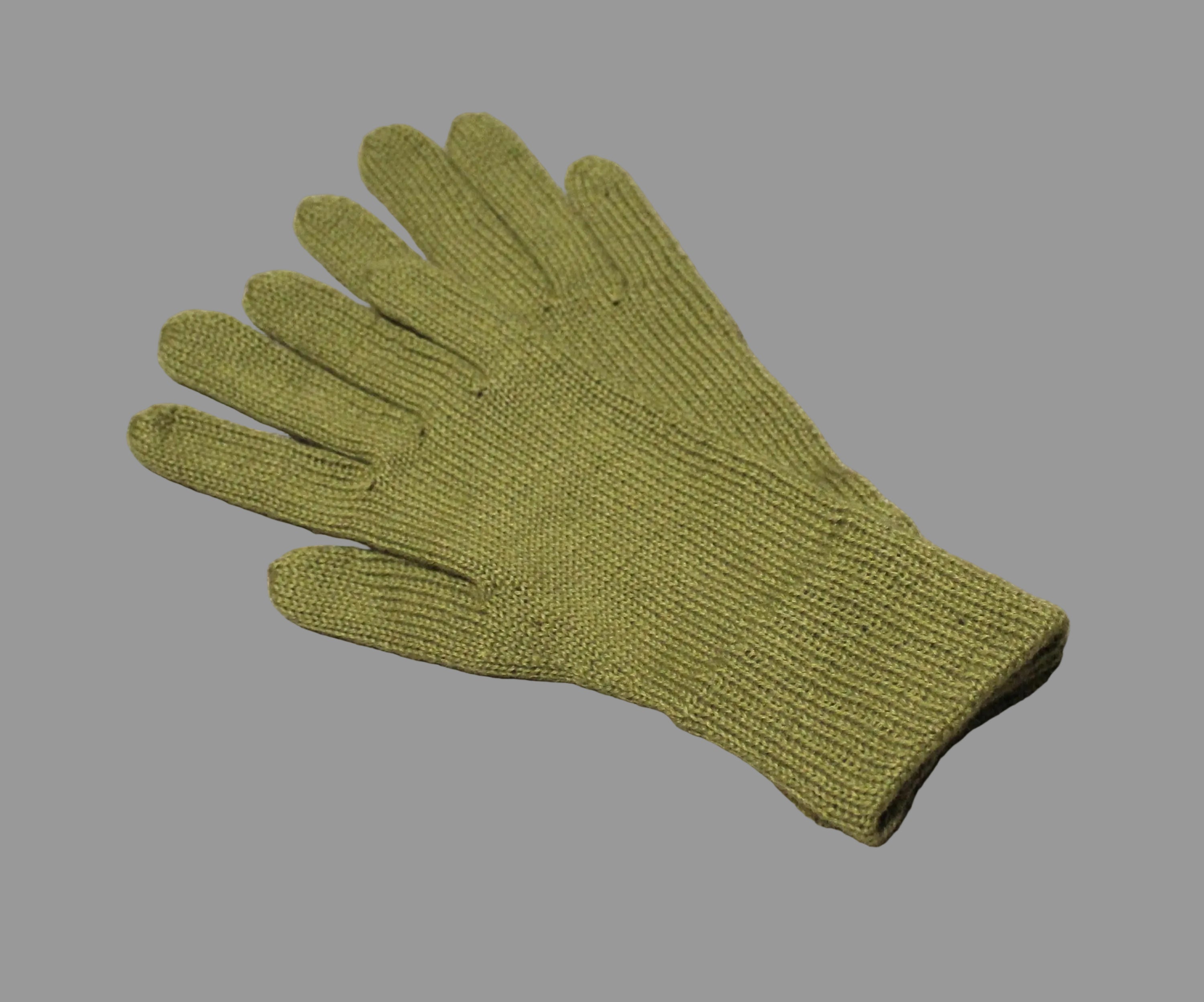 Green knitted glove on a textured beige surface
