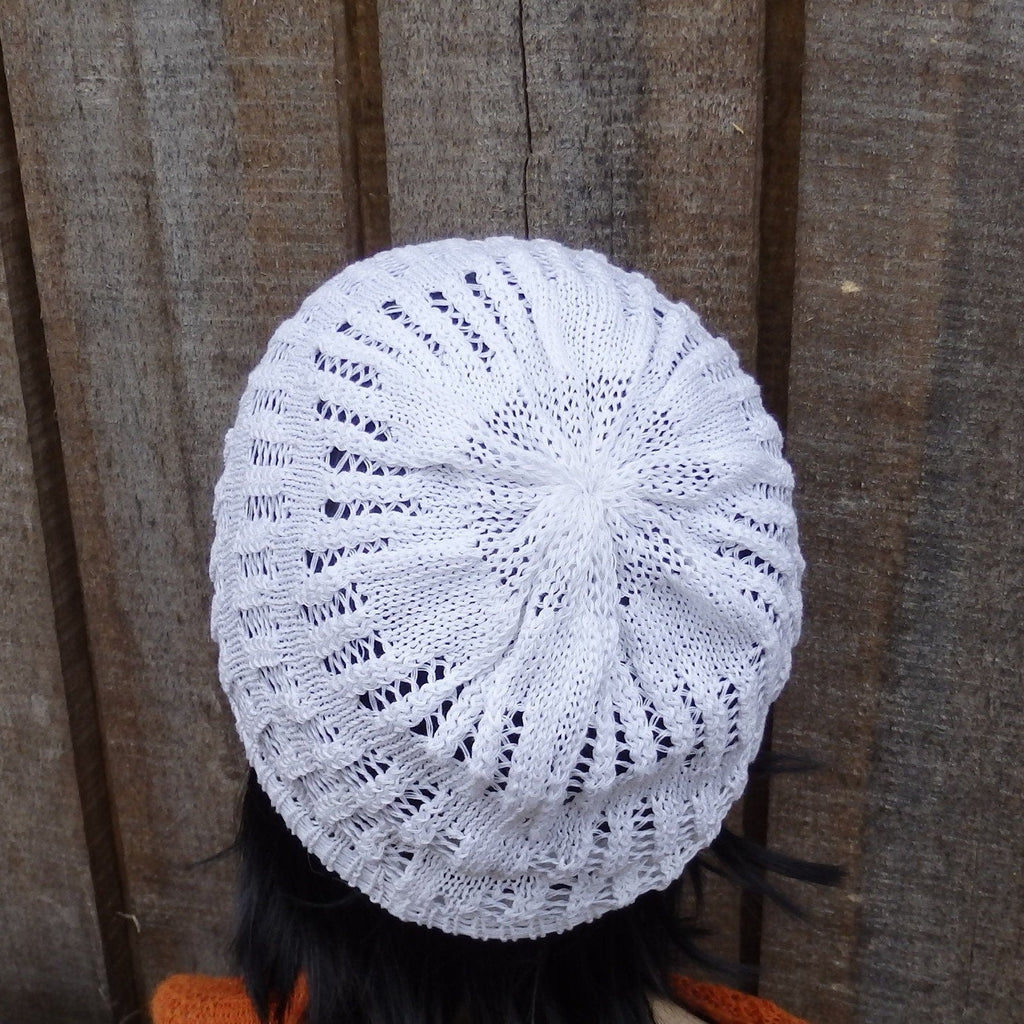 White knitted hat on a person against a wooden fence background