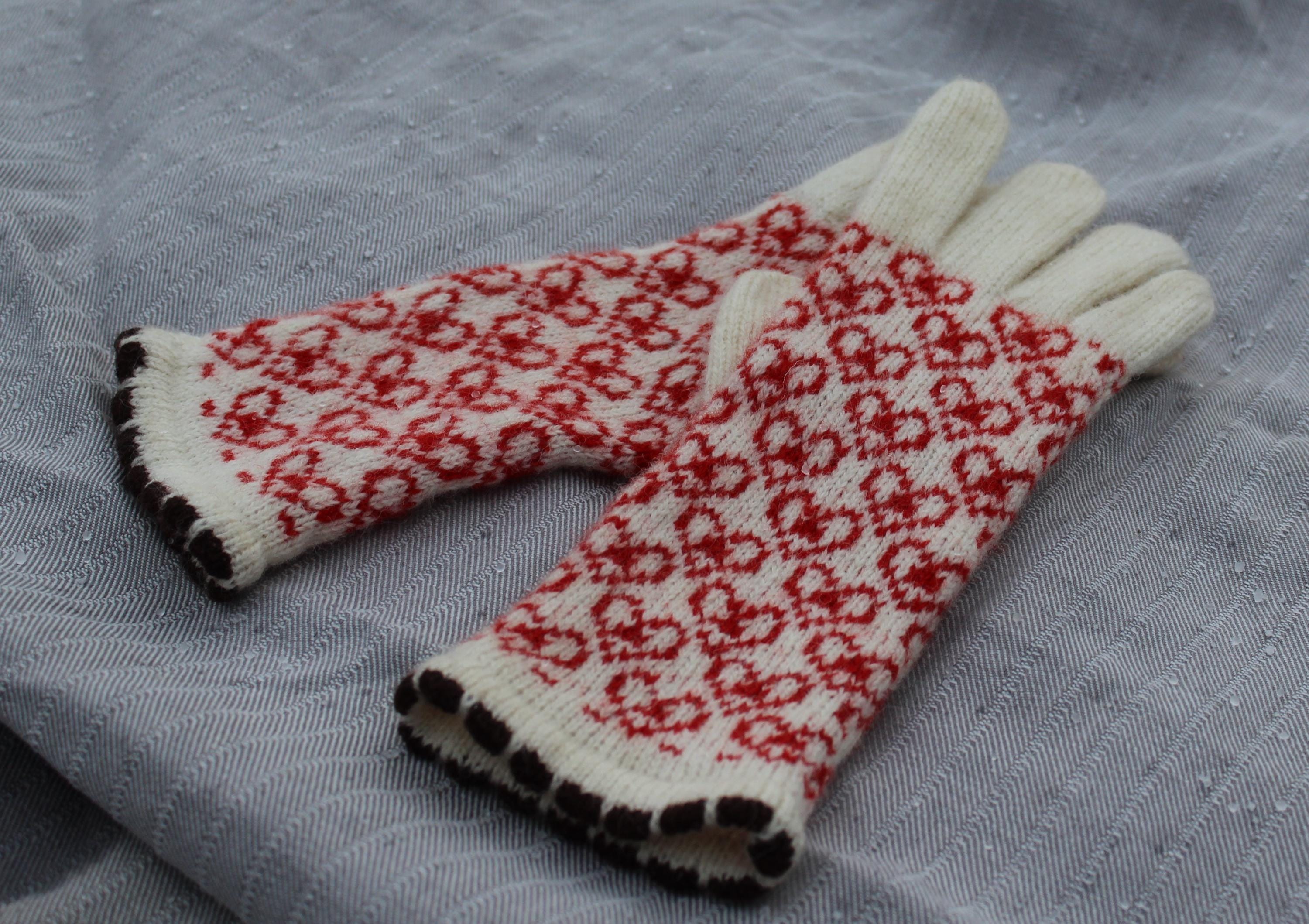 Pair of gloves with red and black pattern on a gray fabric background