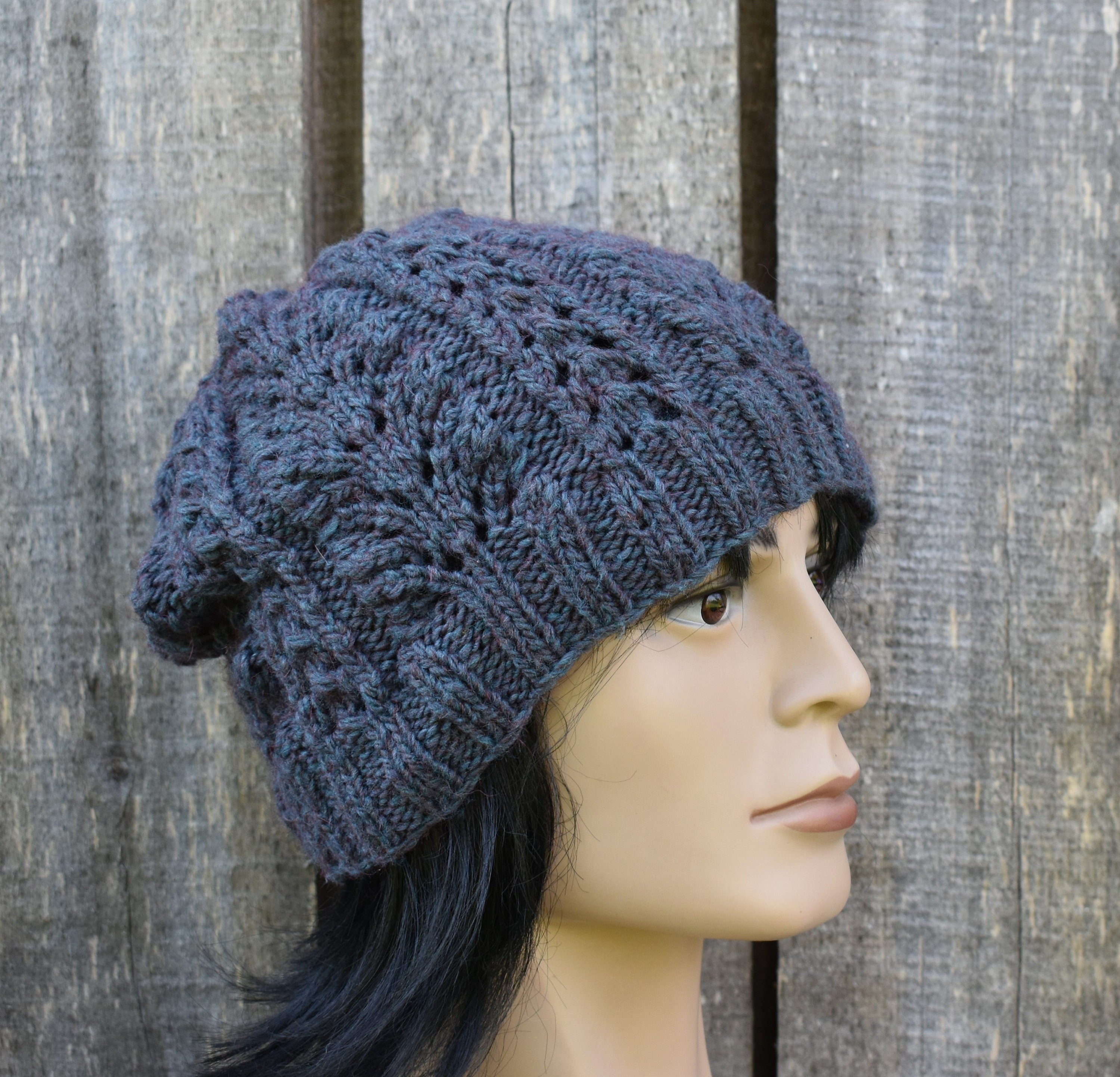 Blue knitted beanie worn by a mannequin against a wooden background