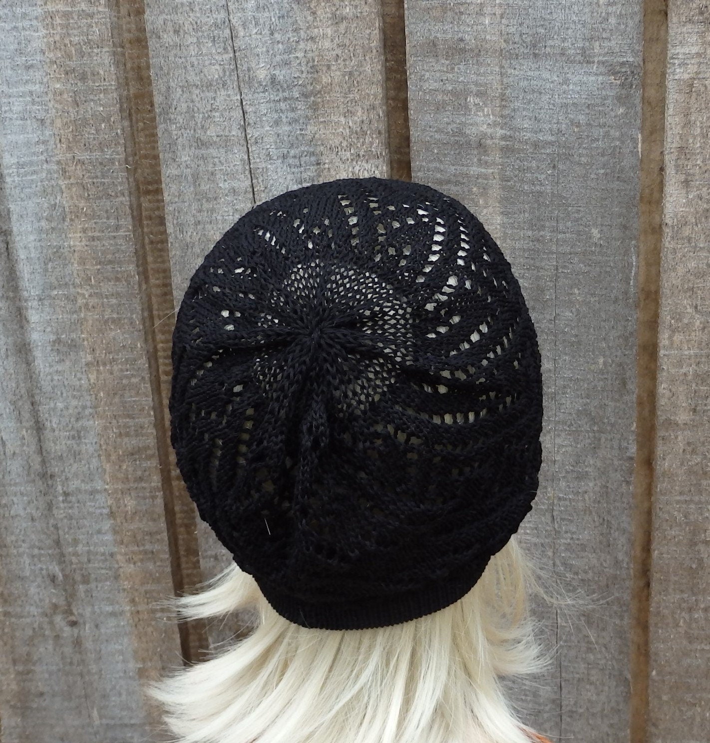 Black knitted beanie on a mannequin head against a wooden background