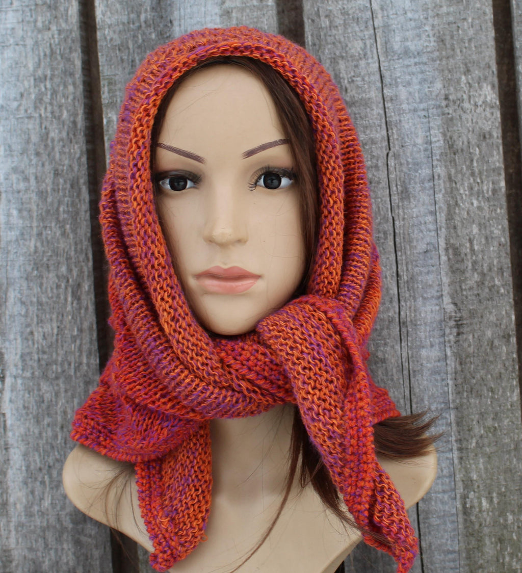 Mannequin head wearing a knitted orange scarf against a wooden background