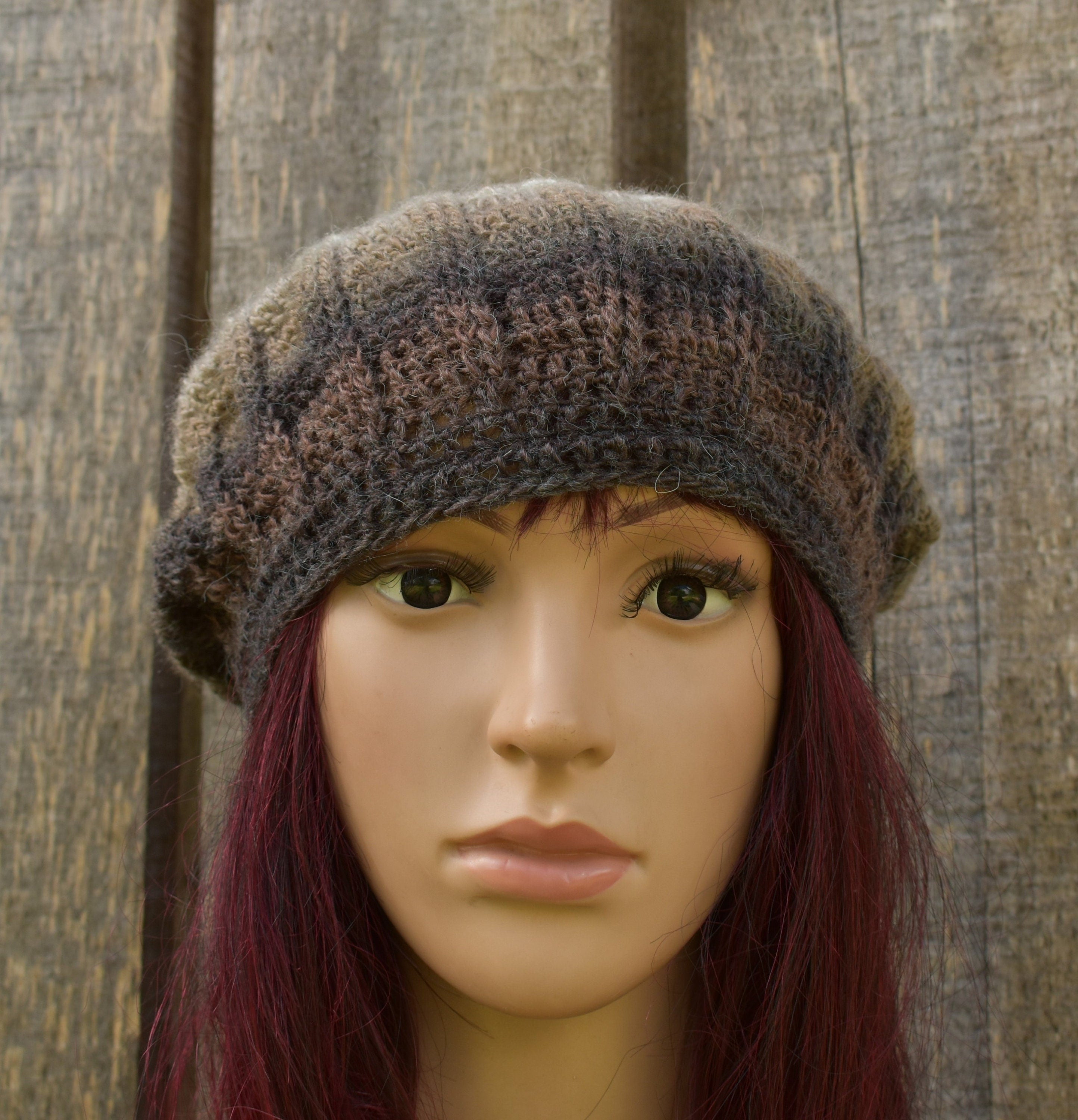 Knitted brown hat on a mannequin head against a wooden background