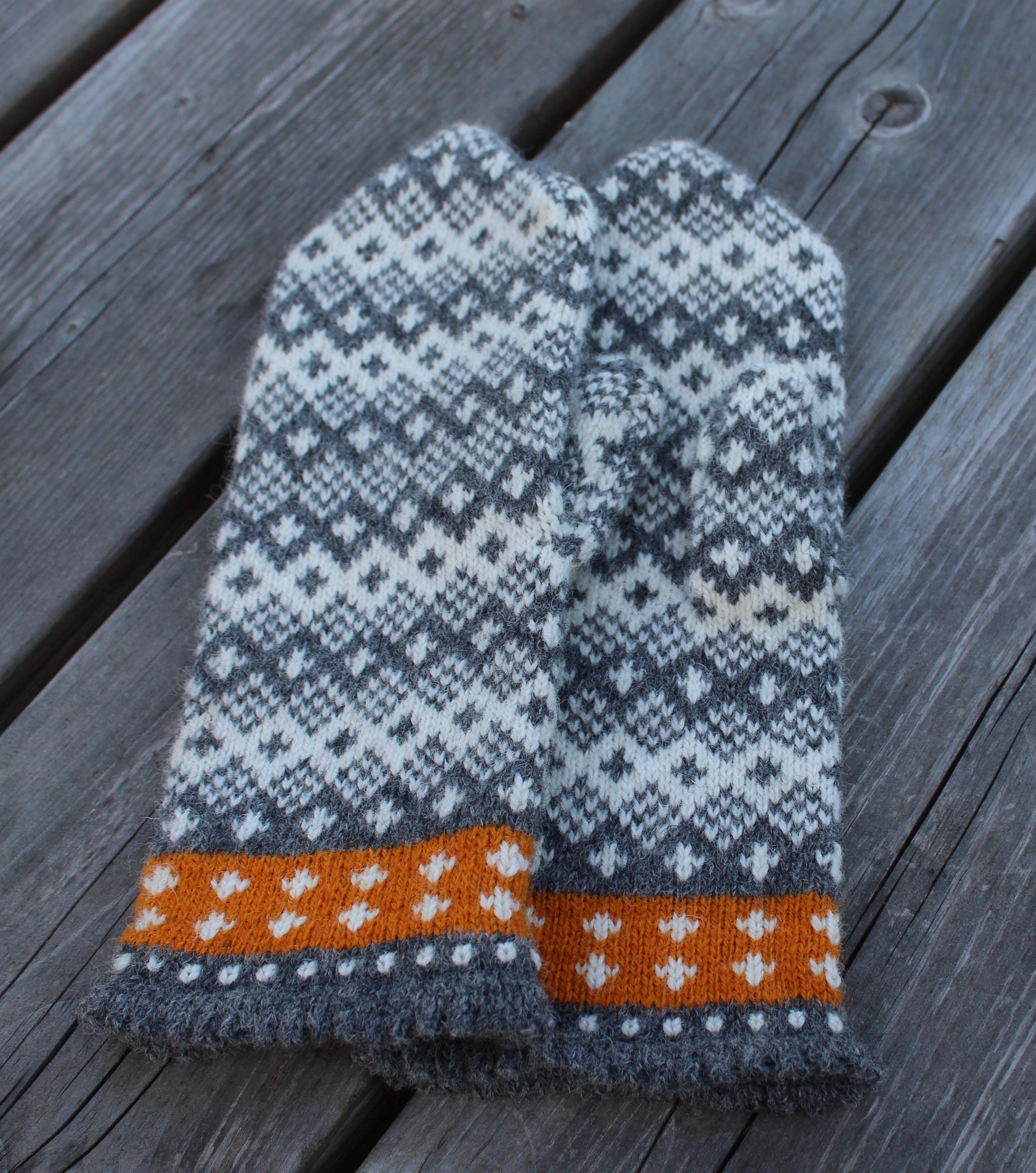Pair of knitted mittens with a pattern on a wooden surface