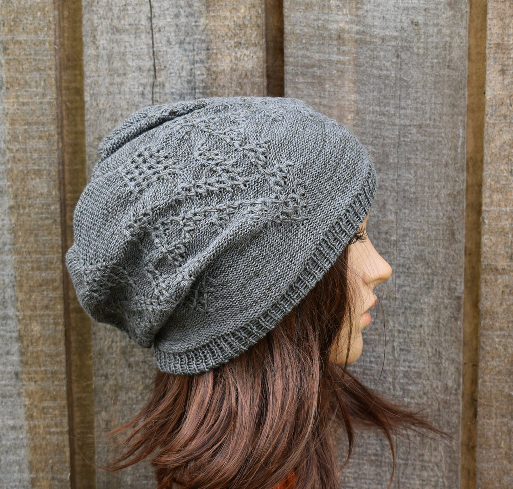 Person wearing a gray knit hat against a wooden background