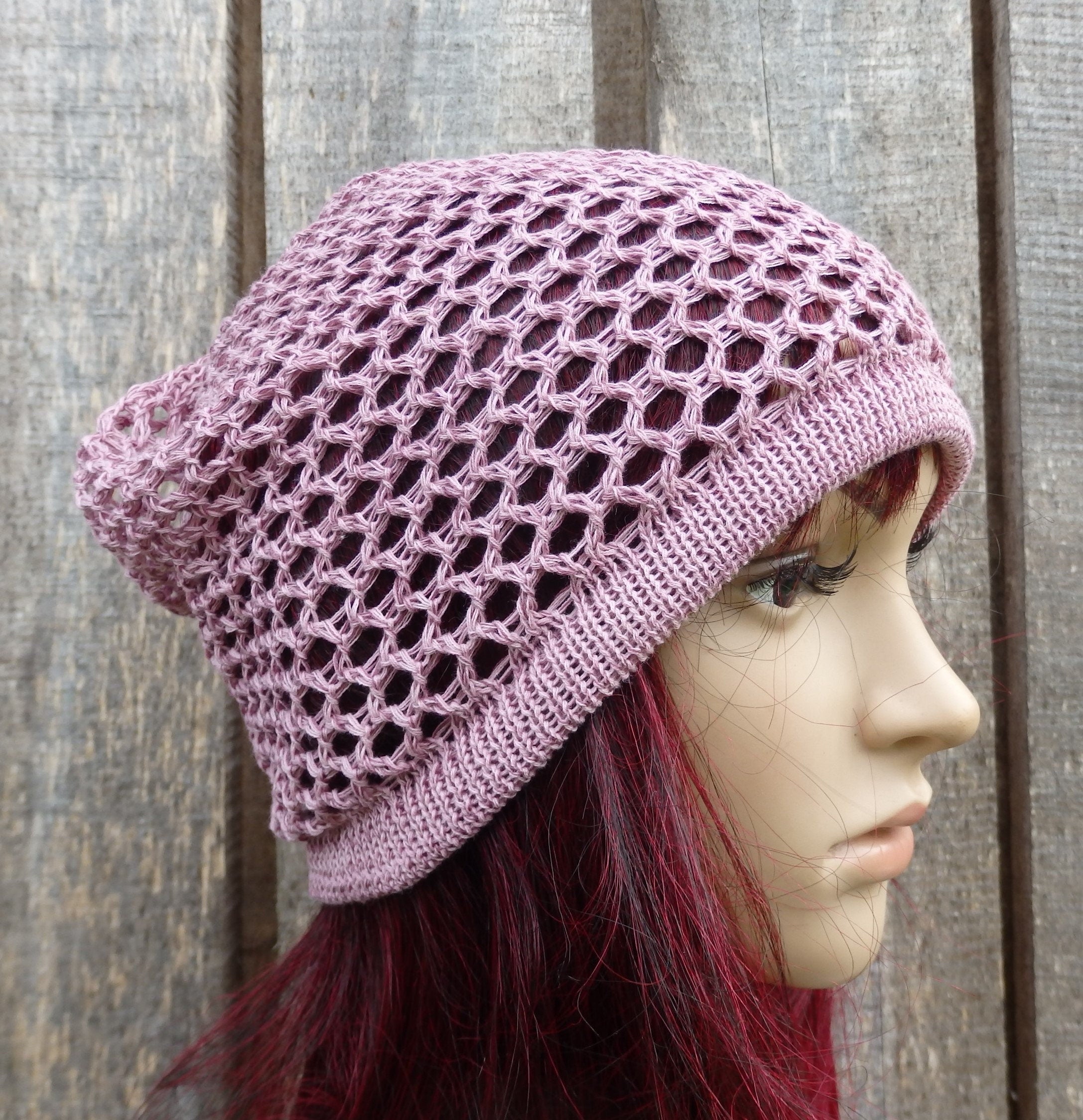 Pink crochet hat worn by a mannequin against a wooden background