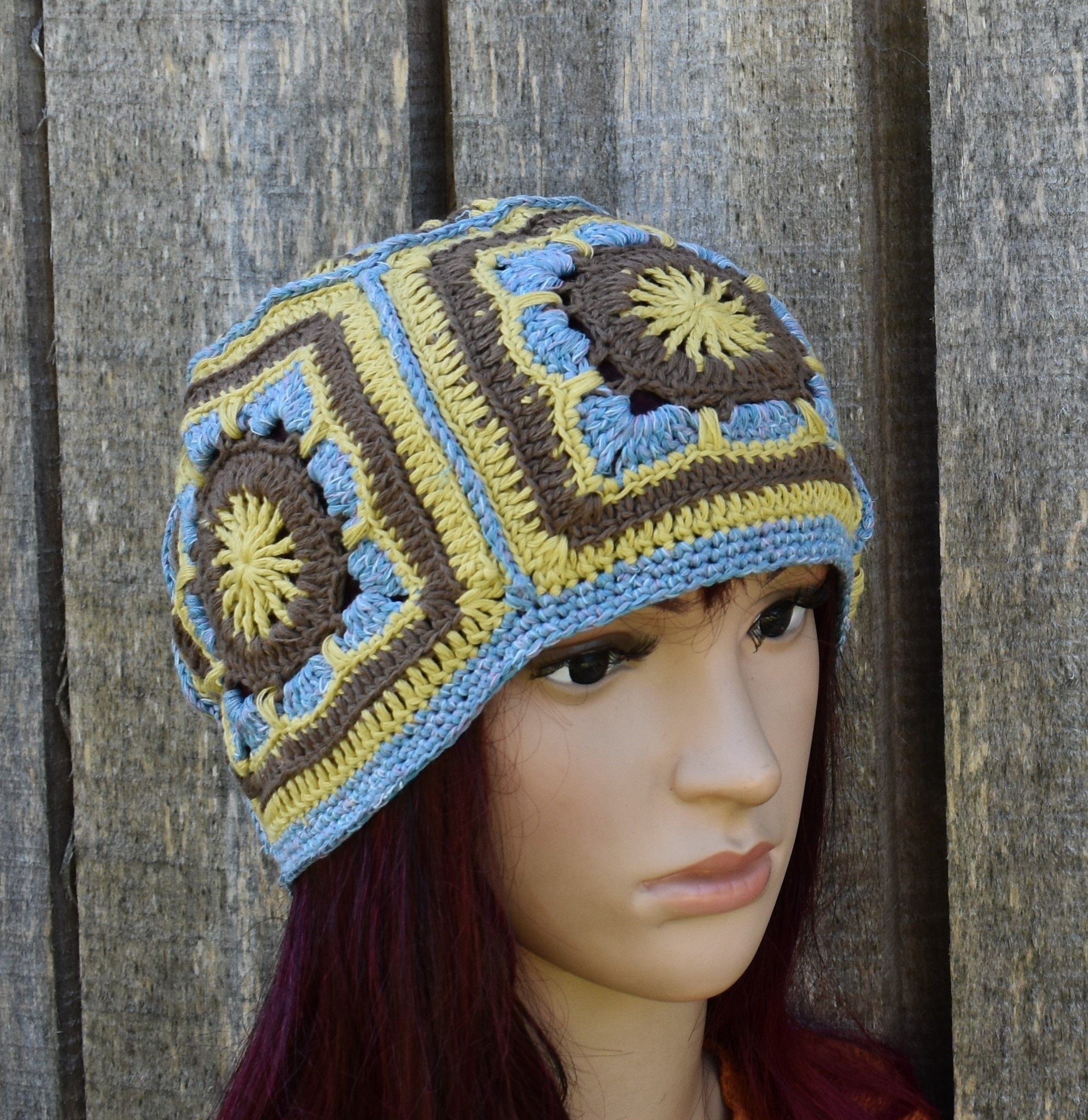 Crocheted hat with geometric pattern on a mannequin head against a wooden background