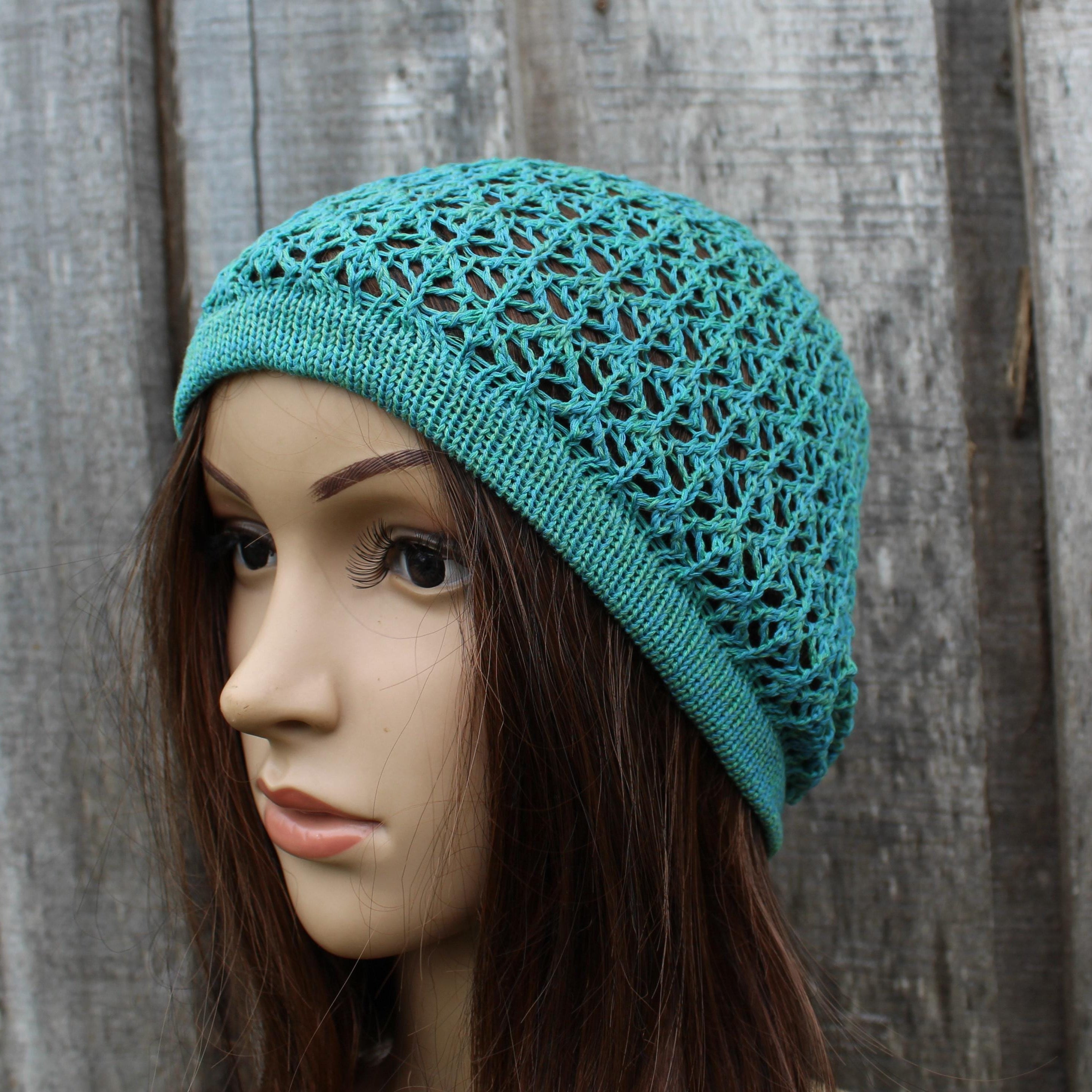 Teal knitted hat on a mannequin head against a wooden background