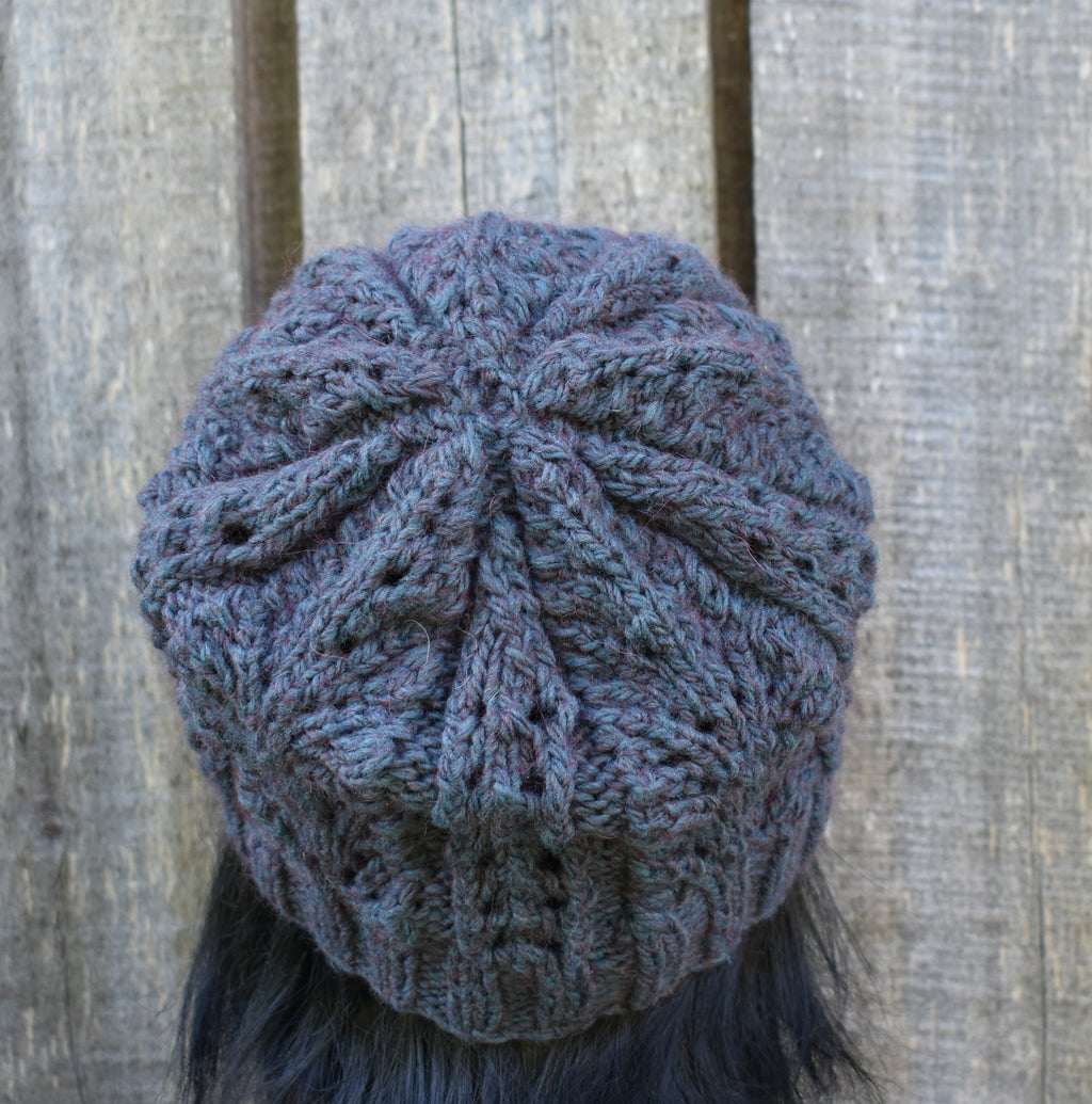 Blue knitted beanie on a person against a wooden background