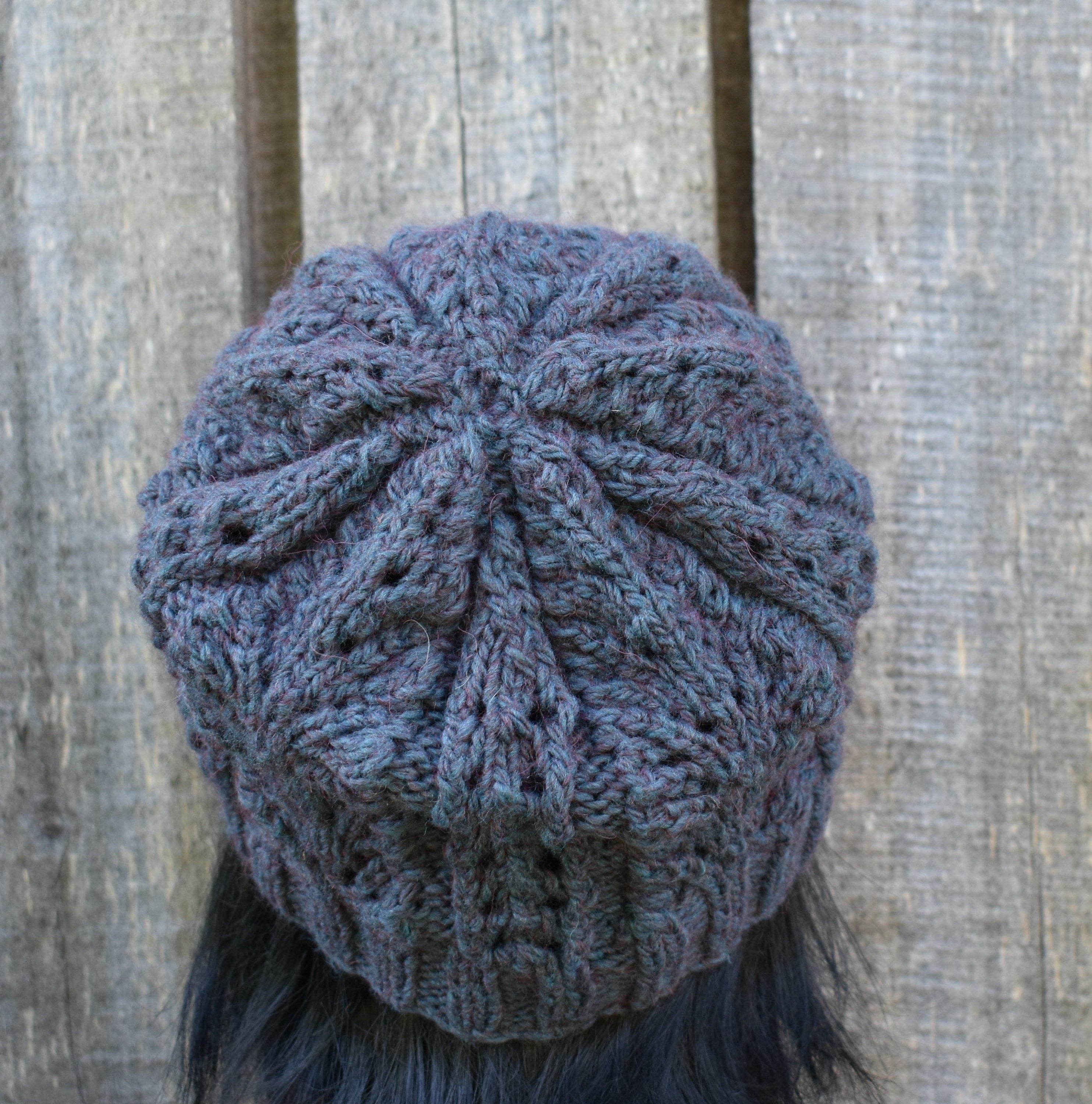 Blue knitted beanie on a person against a wooden background