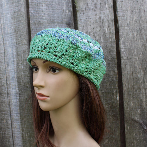 Green crocheted beanie on a mannequin head against a wooden background