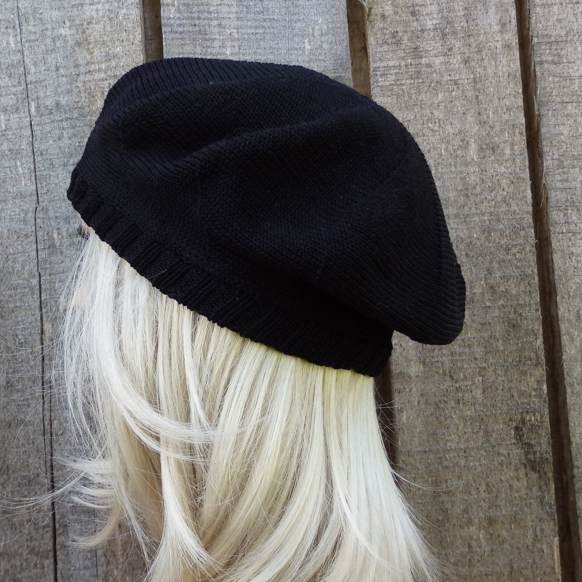 Black beanie on a mannequin head with blonde hair against a wooden background