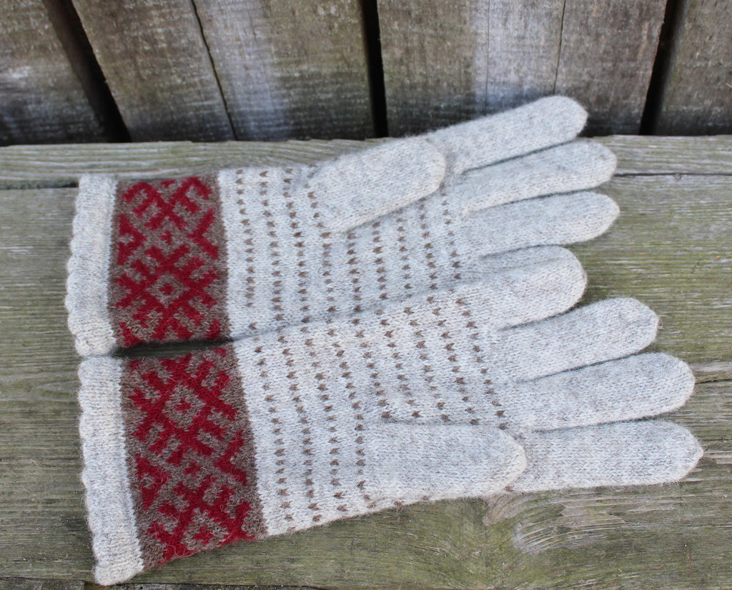 Pair of gray gloves with red pattern on a wooden surface